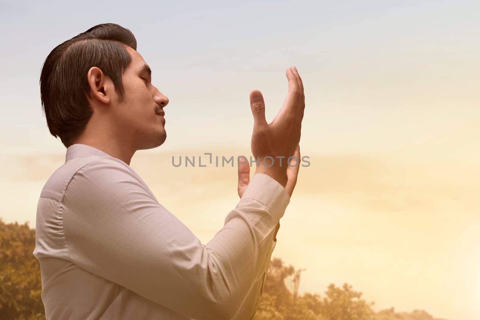 Handsome asian muslim man with traditional dress praying during sunset