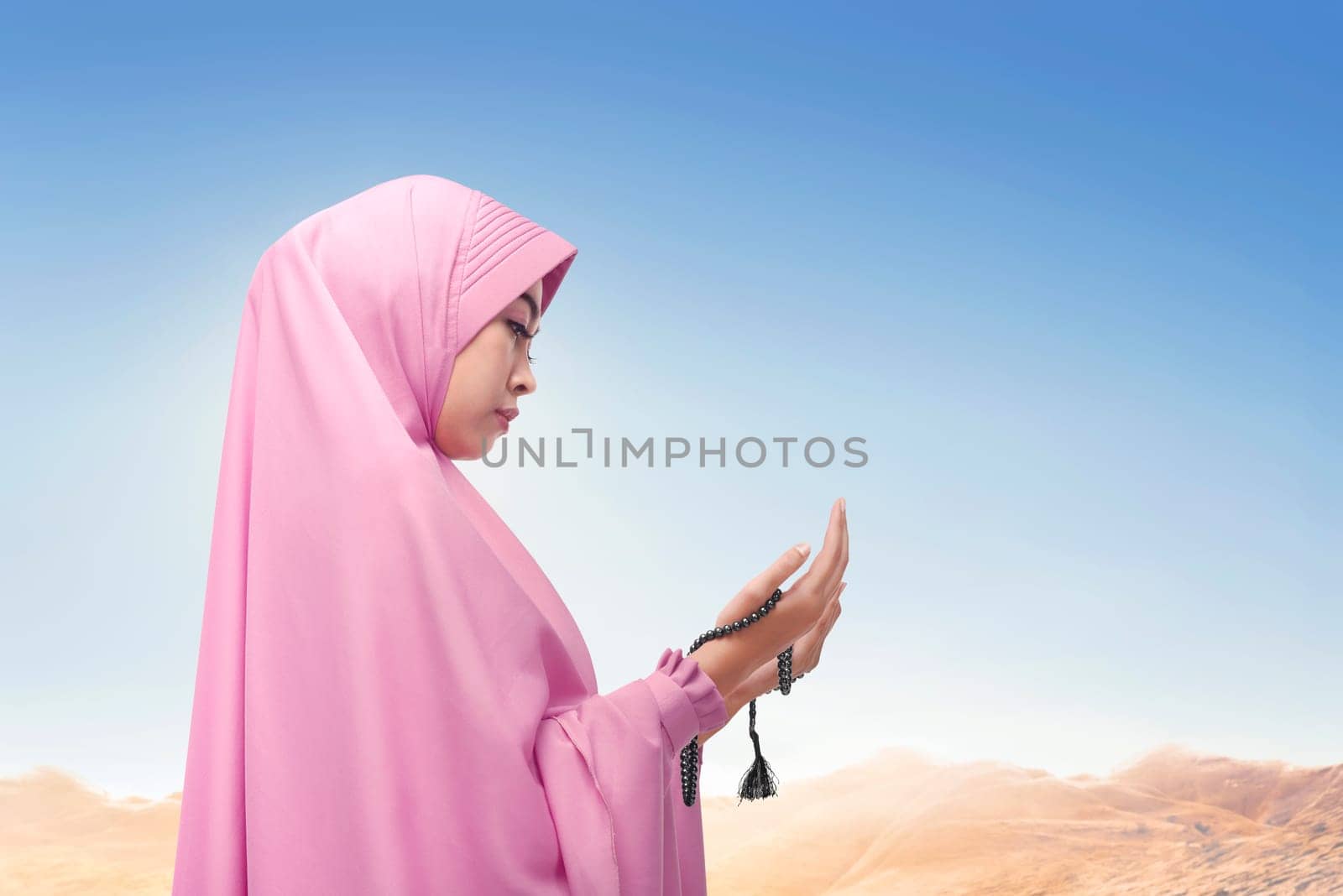 Religious asian muslim woman wearing veil praying with sunlight at sky