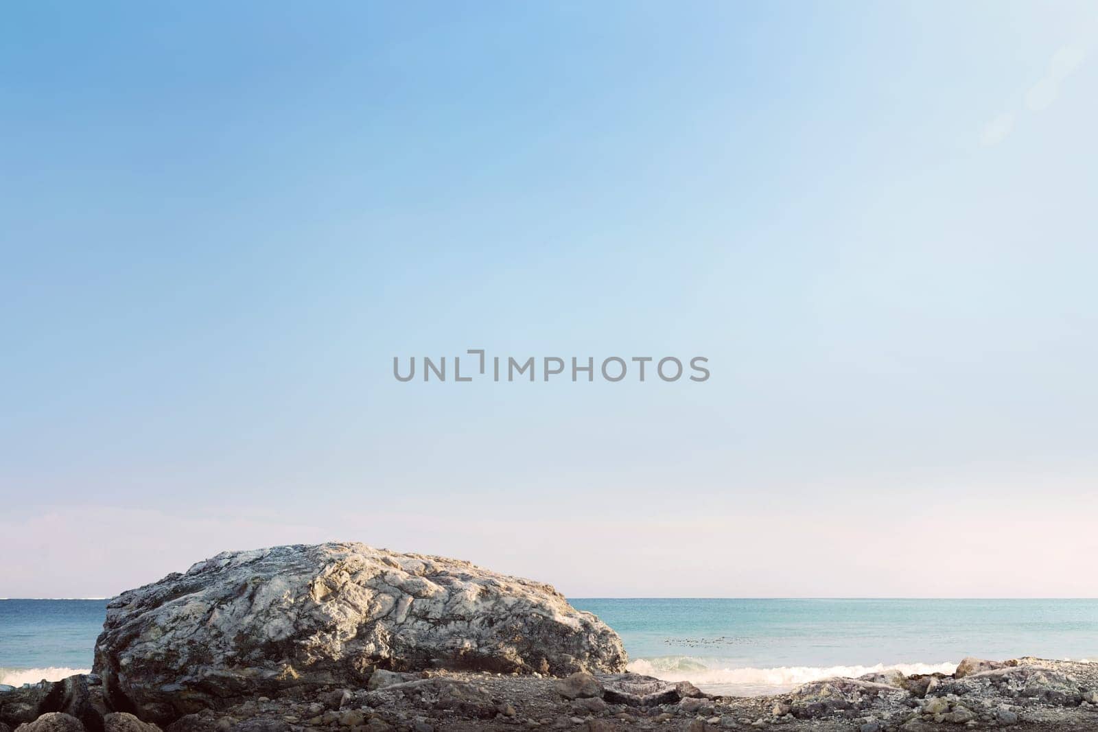 Giant rock and sea waves with blue sky at sunny day