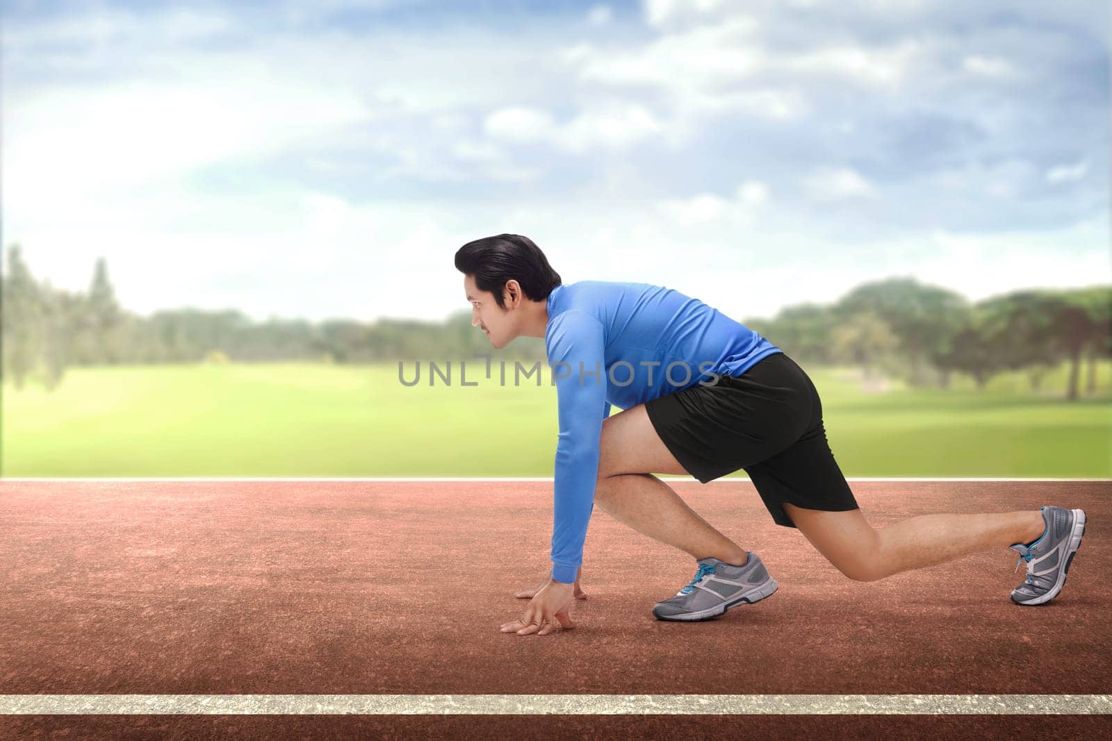 Young asian runner in start position ready to running on race track