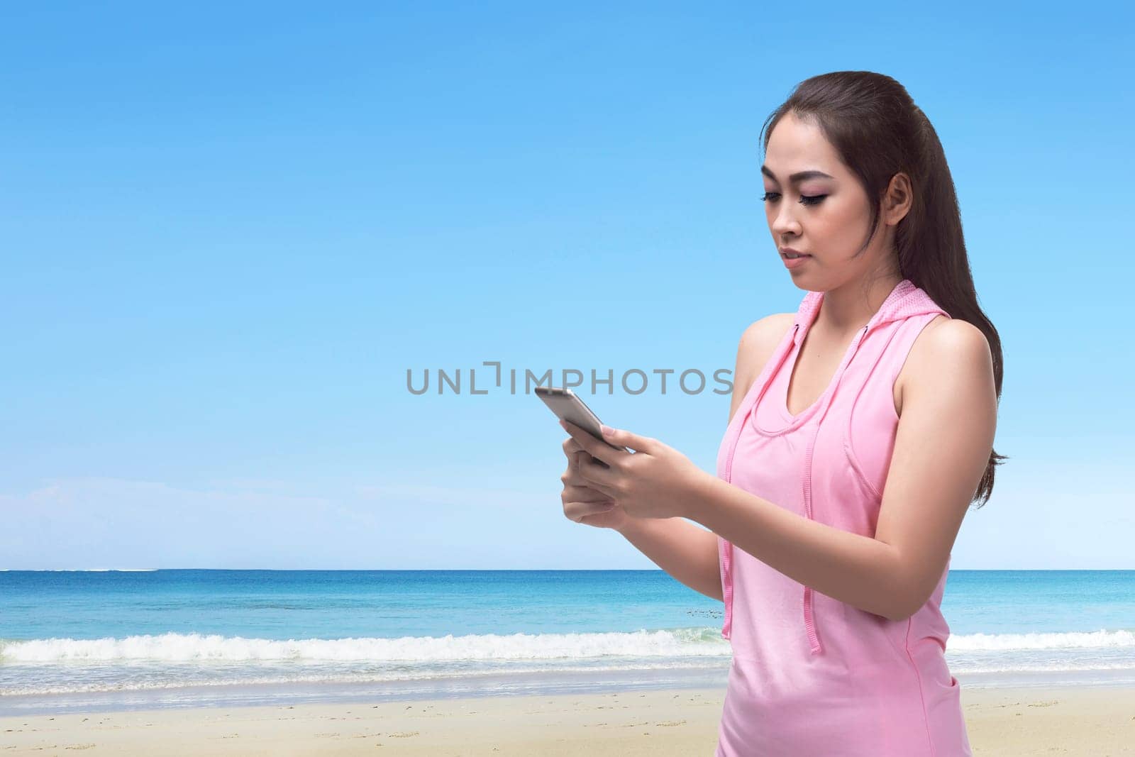 Beautiful asian woman walking while using her phone in the beach