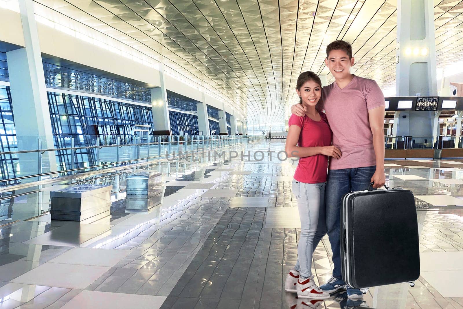Smiling asian couple holding luggage bags to traveling at airport