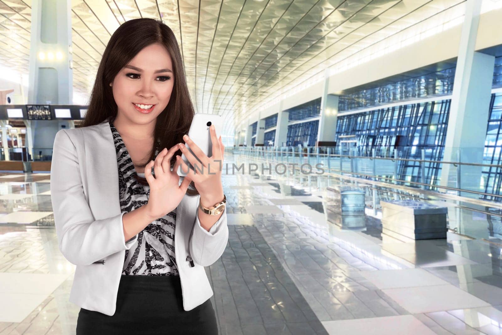 Beautiful asian business woman chatting on her mobile phone while standing in modern building