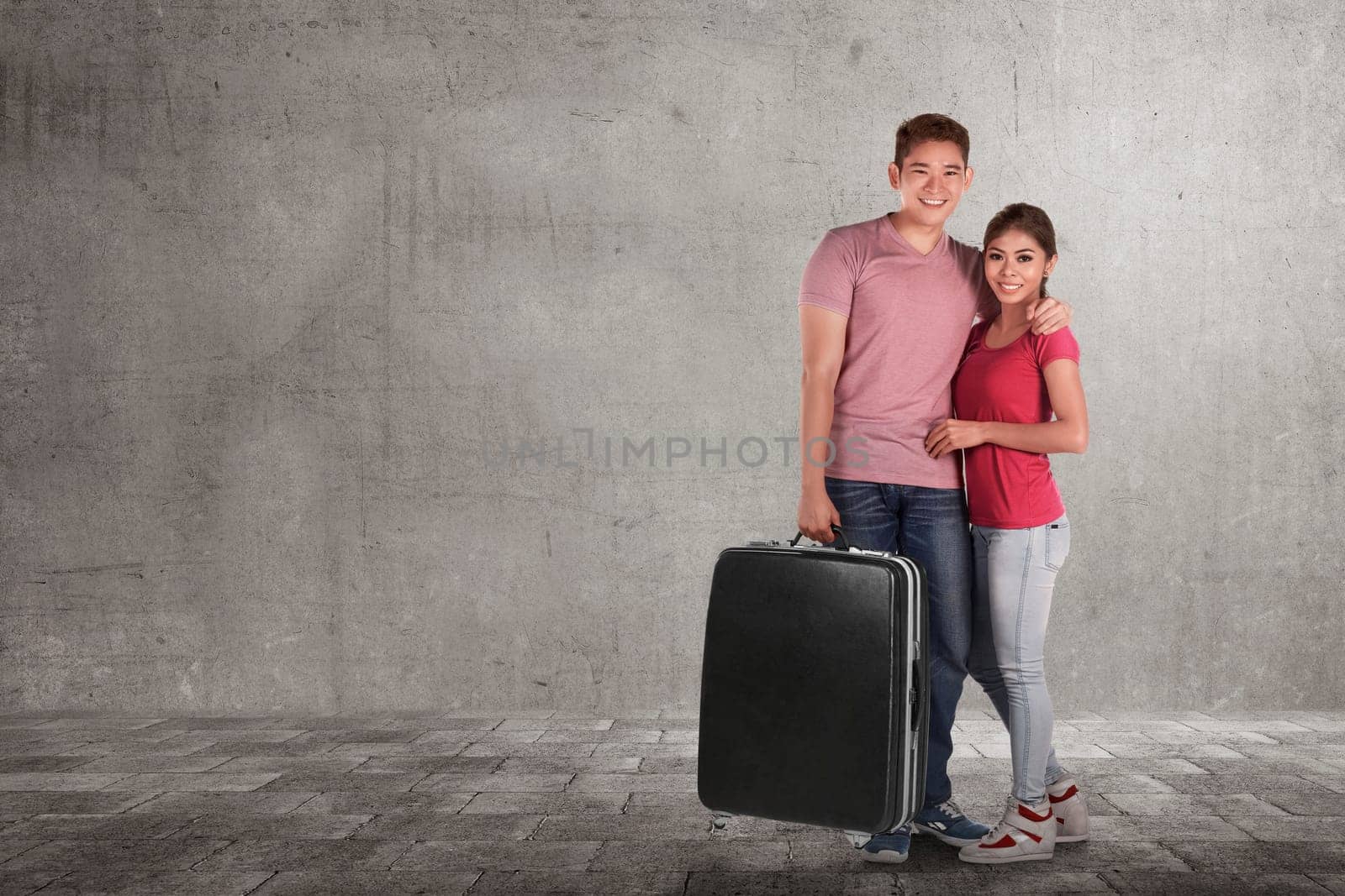 Loving asian couple vacations with luggage bags against grey wall background