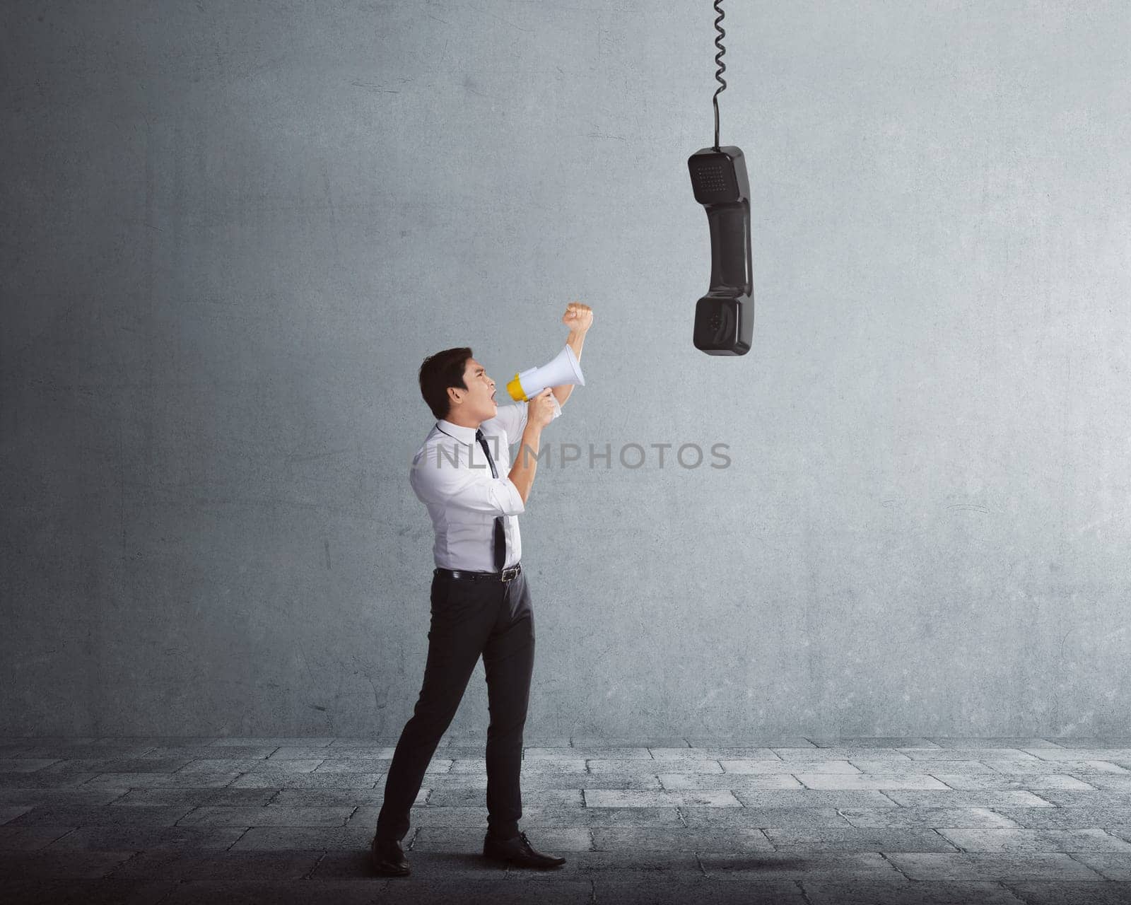Young asian businessman talking in megaphone to receiver with gray background