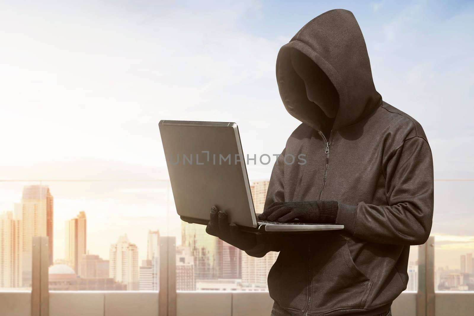 Hacker man with anonymous mask using laptop to hacking in the modern building