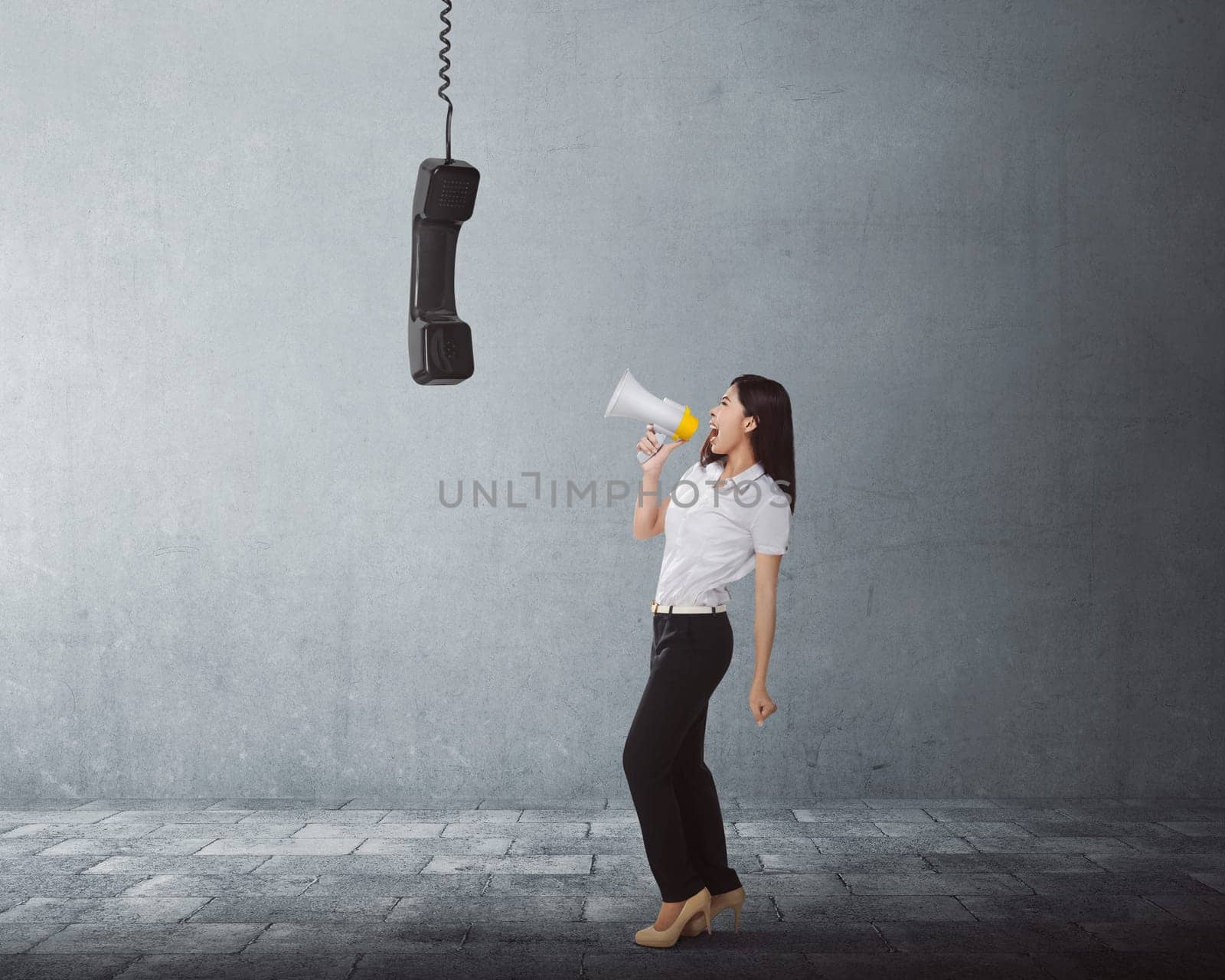 Young asian business woman screaming using a megaphone to black receiver in the city street