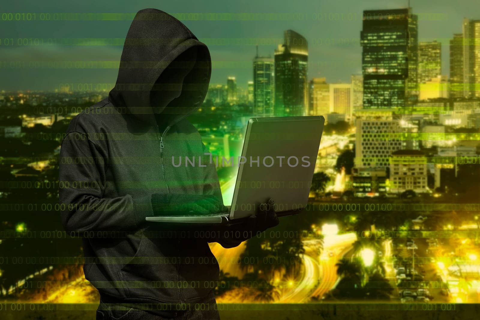 Hacker man with mask typing on laptop against modern city background