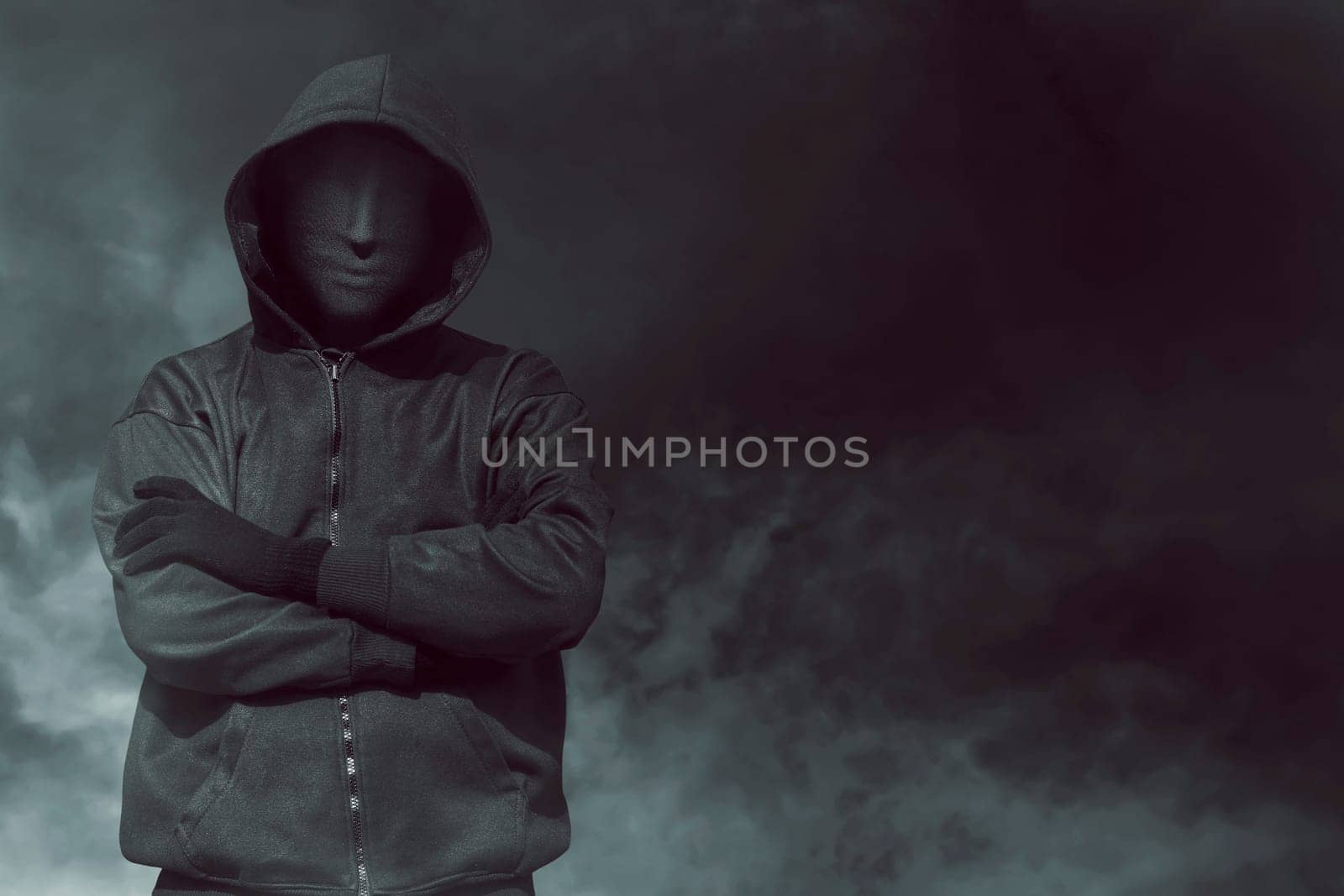 Hooded man with mask standing alone in the empty dark room