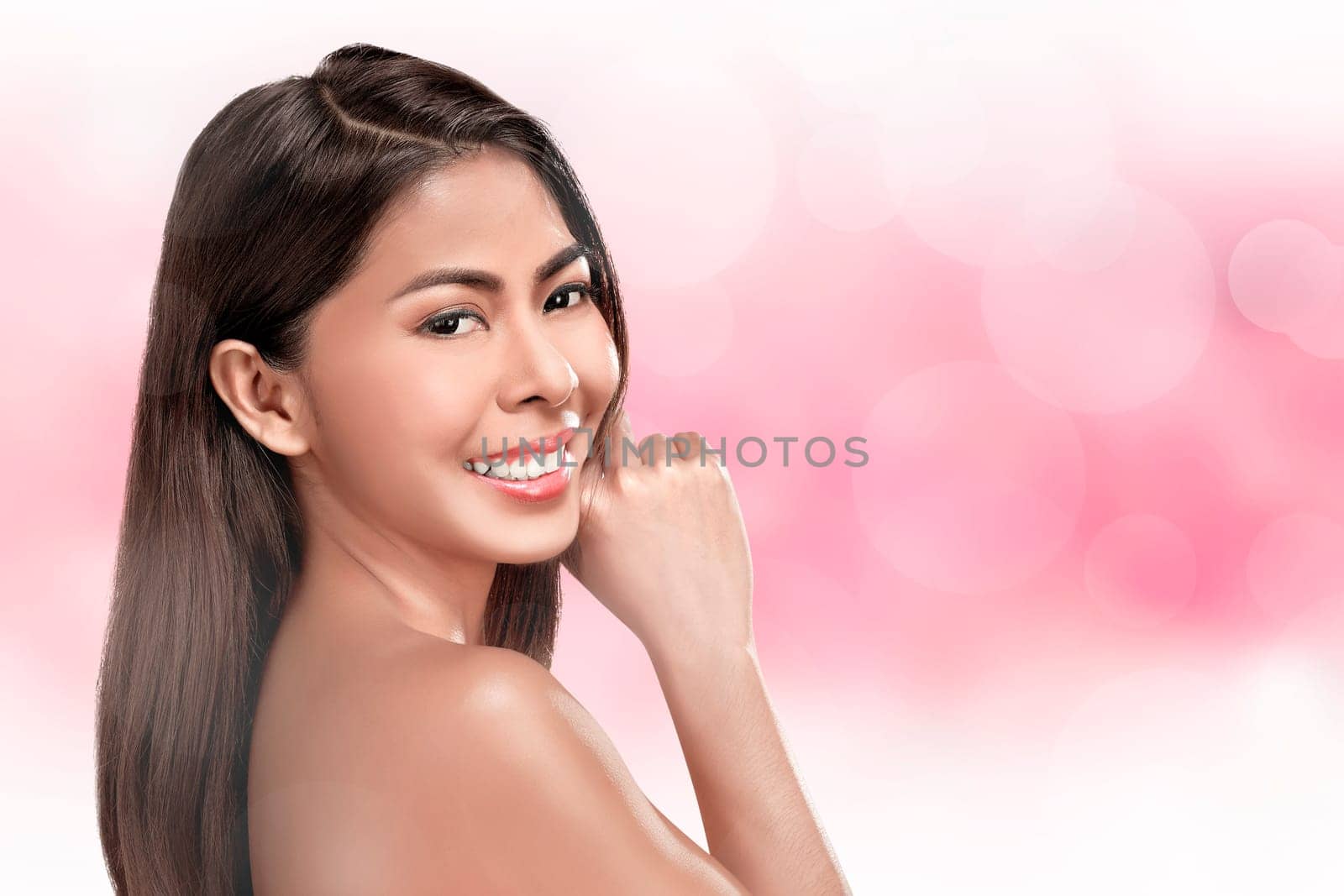 Smiling asian woman with beautiful healthy face on pink background