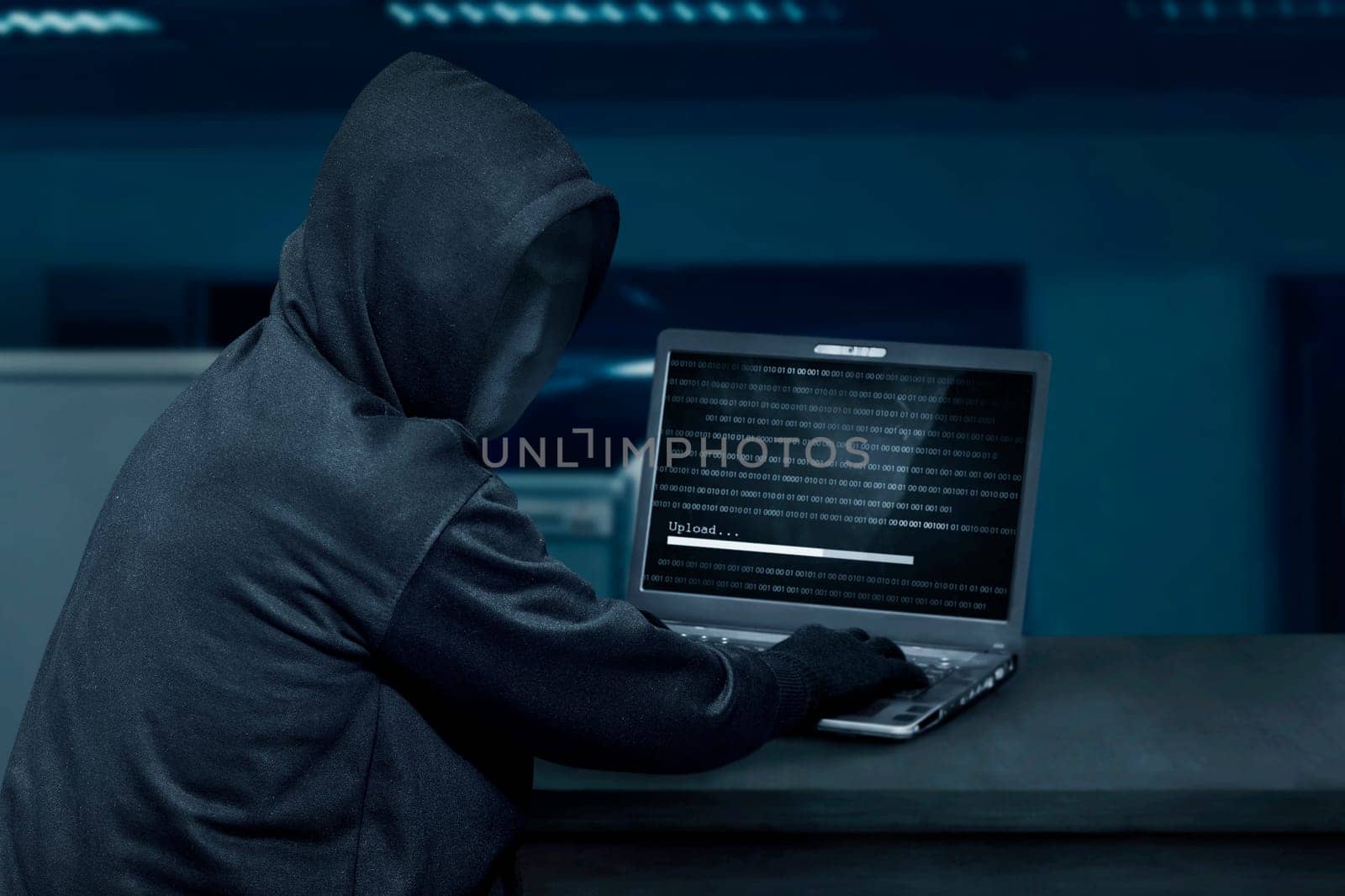 Hacker man wearing mask using laptop to upload computer virus in the office