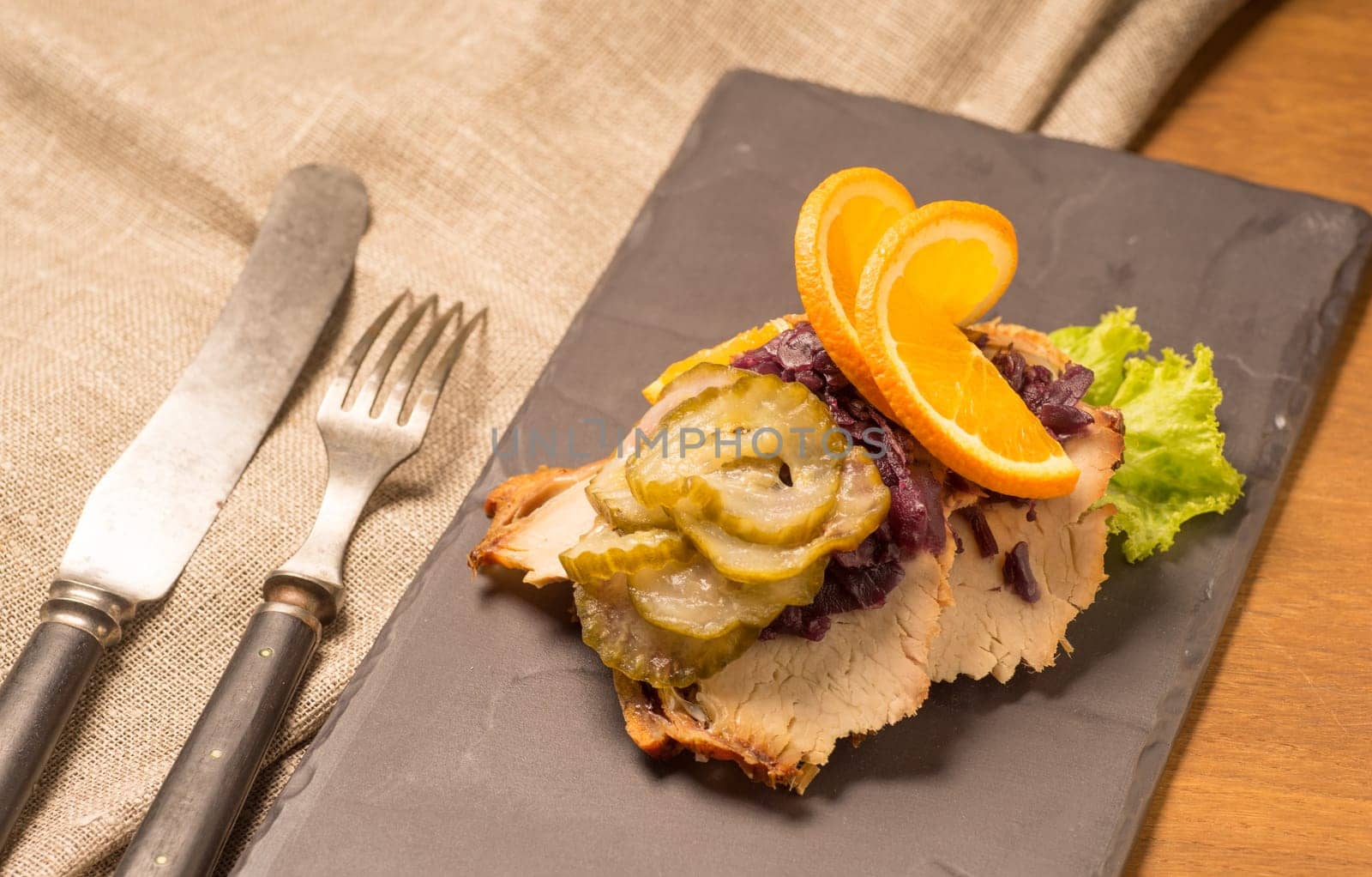 Danish specialties and national dishes, high-quality open sandwich. Roasted Pork belly and Pickled red cabbage and orange served on a plate and ready for eating