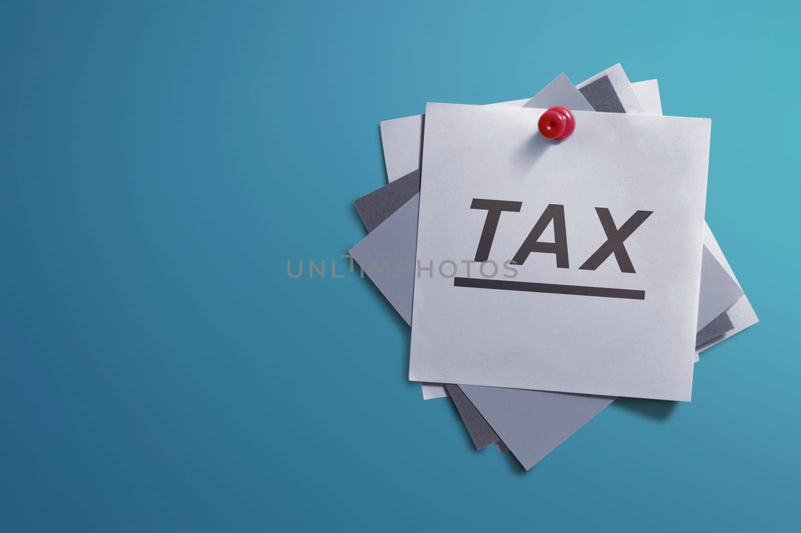 White note paper and written Tax for reminder on blue background