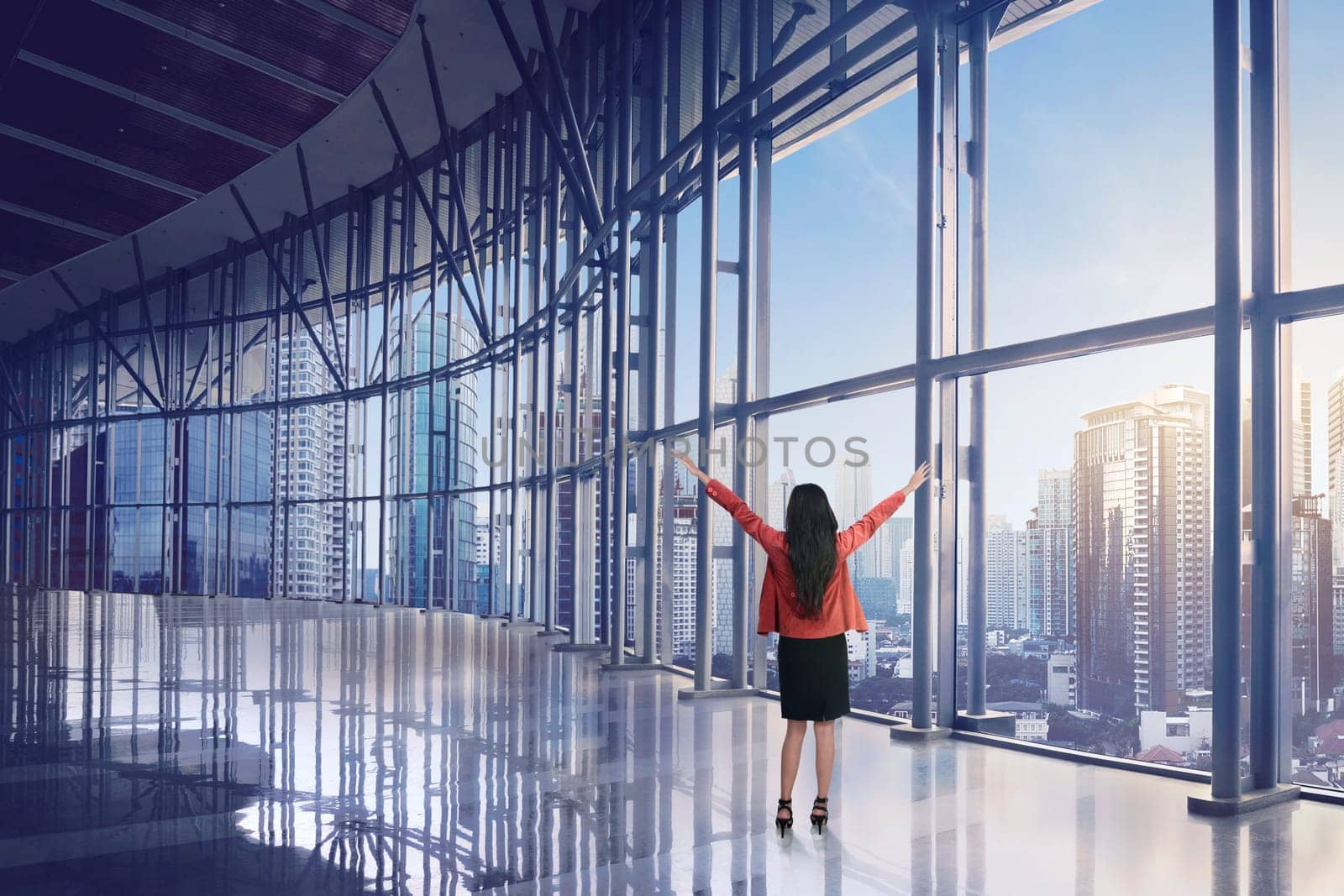 Happy asian business woman looking of skyscraper building from window