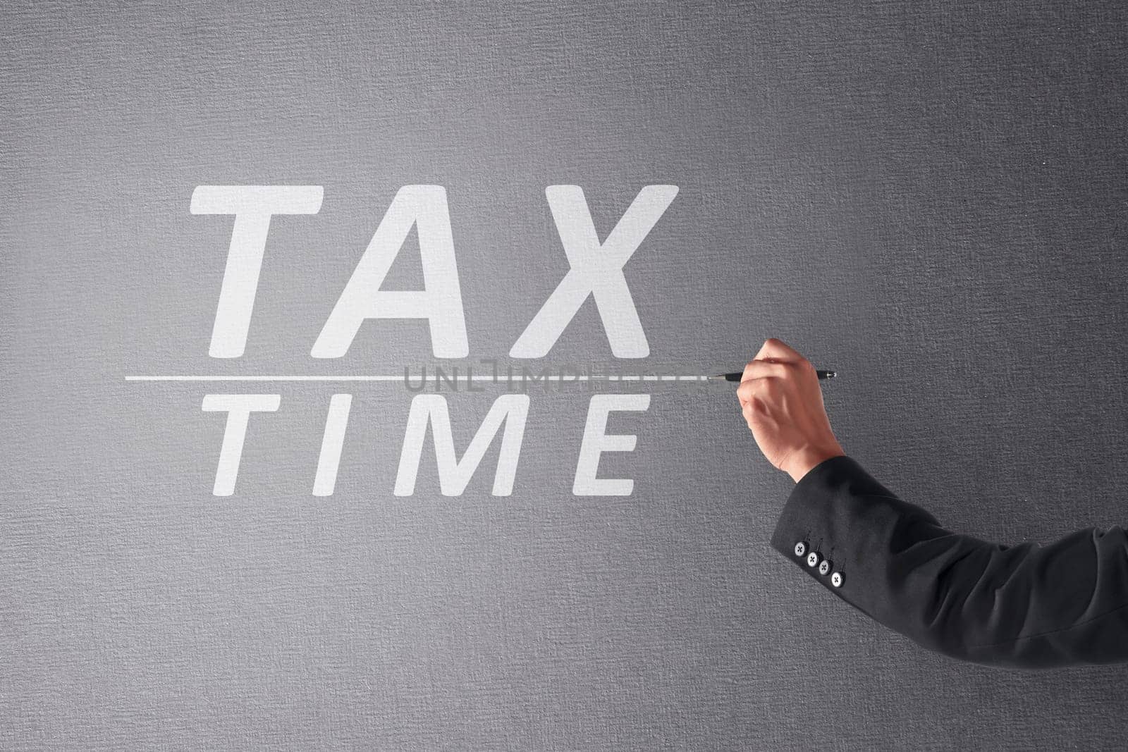 Business person hand writing Tax Time with pen on blackboard