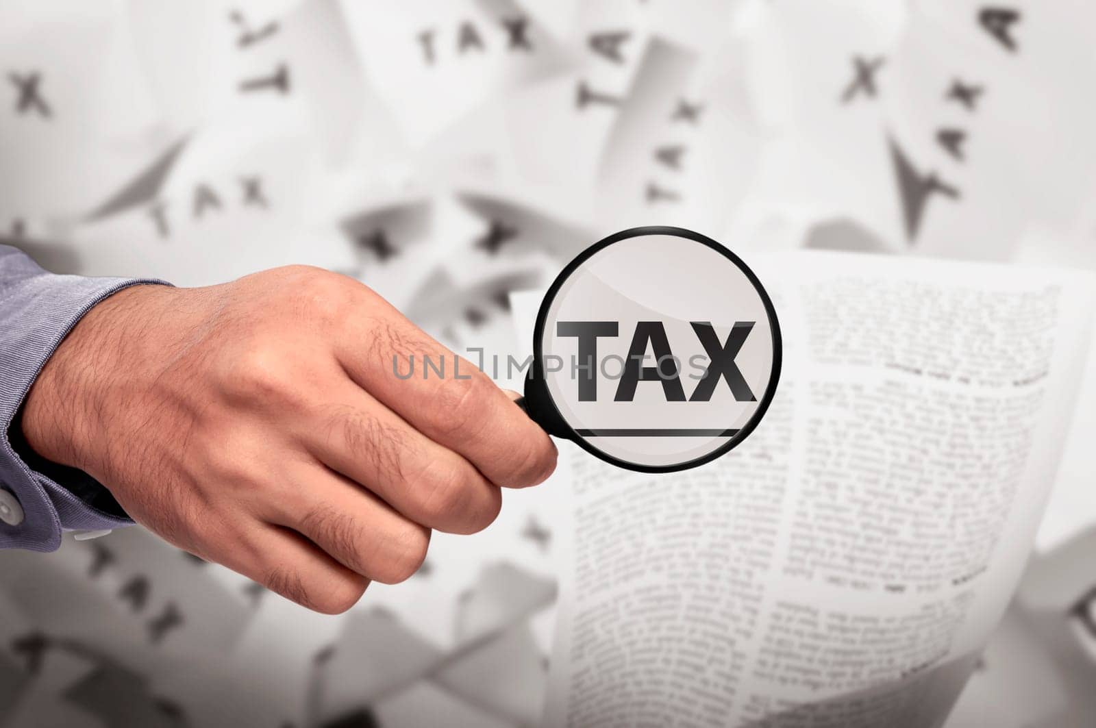 Business hand looking Tax word using magnifying glass on the paper