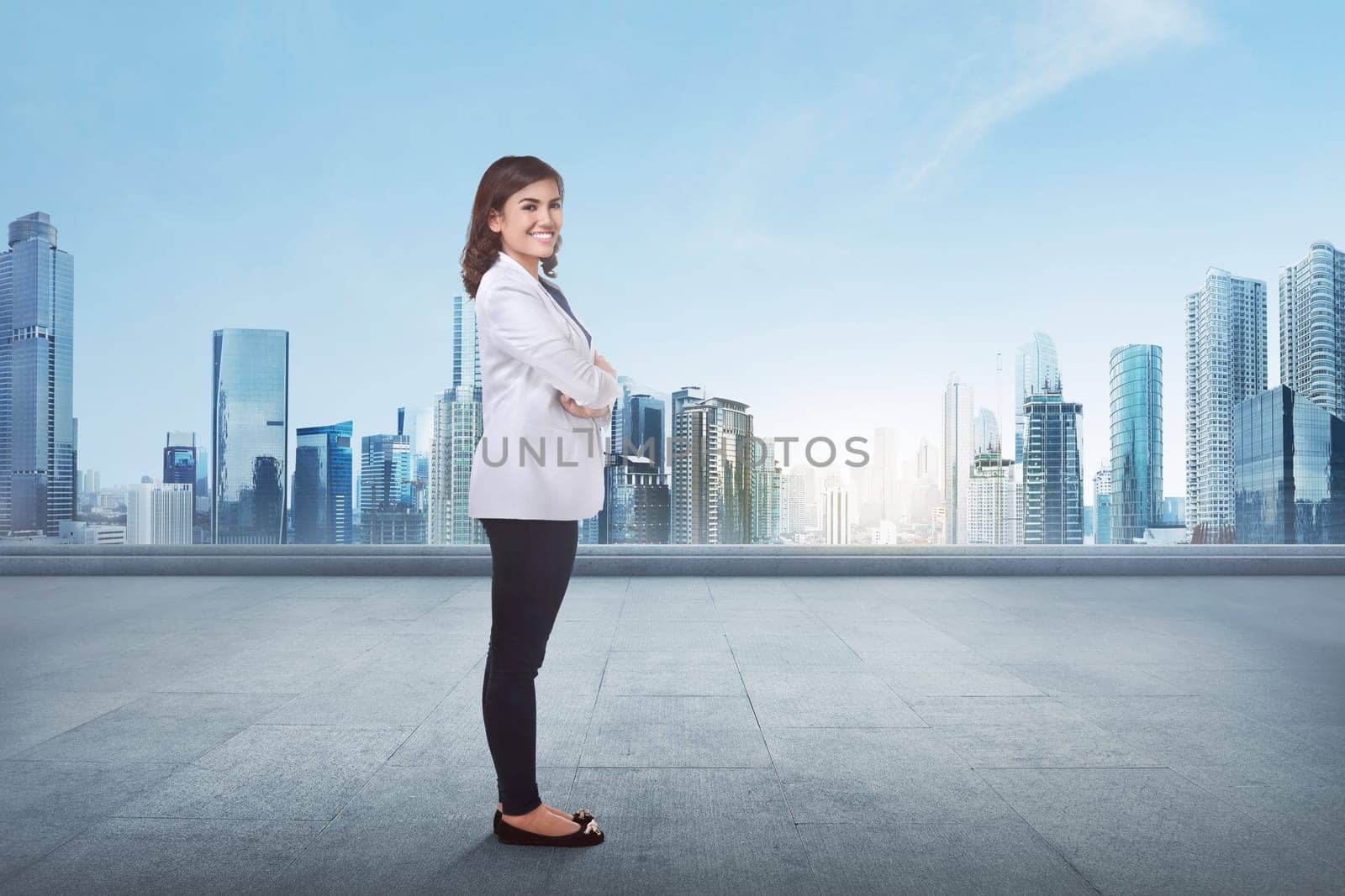 Portrait of a young asian business woman with crossed arm in front of cityscape background