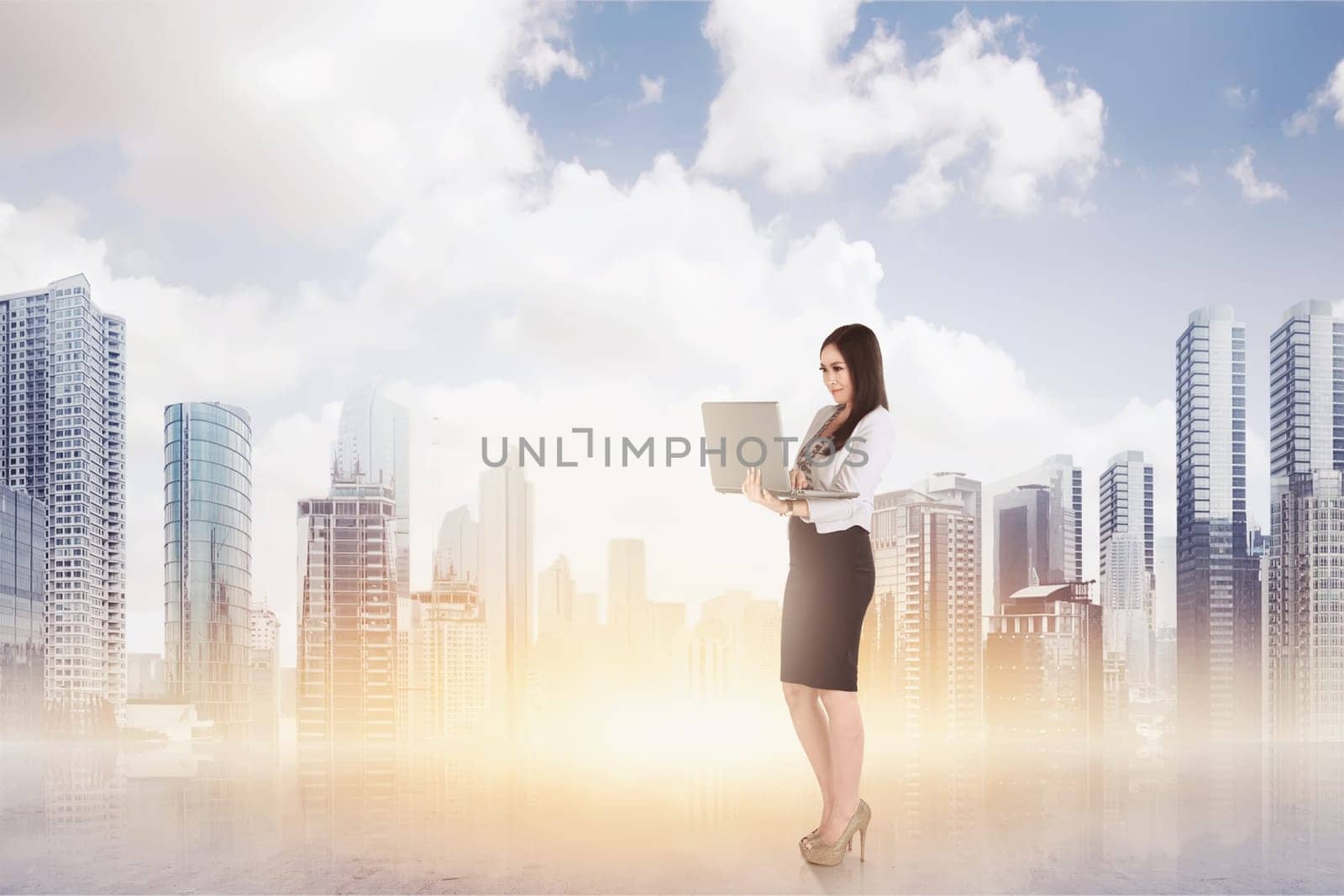 Attractive asian business woman using a laptop while standing against cityscape background
