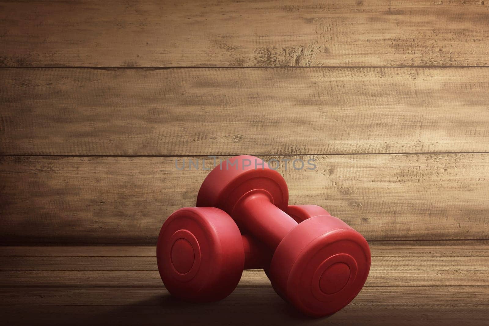 Pair of red dumbbells for workout on wooden rustic background