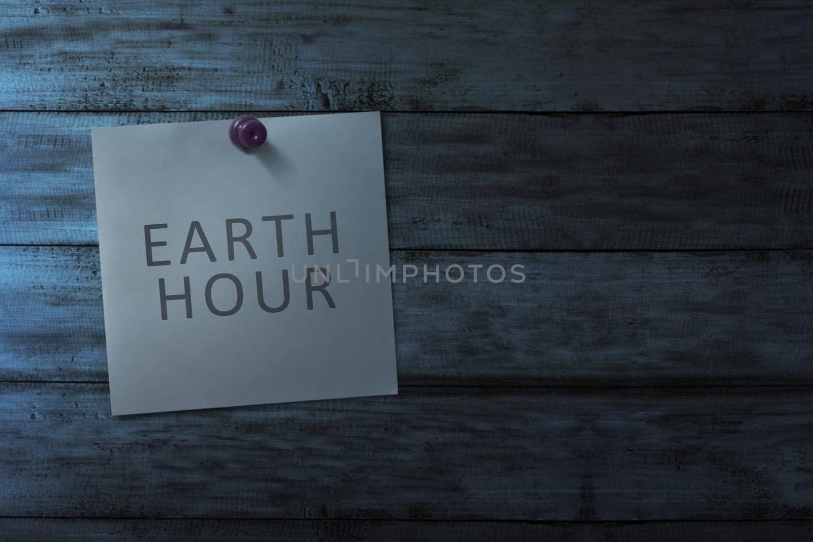 Hanging note paper with earth hour message on wooden wall at dark room background