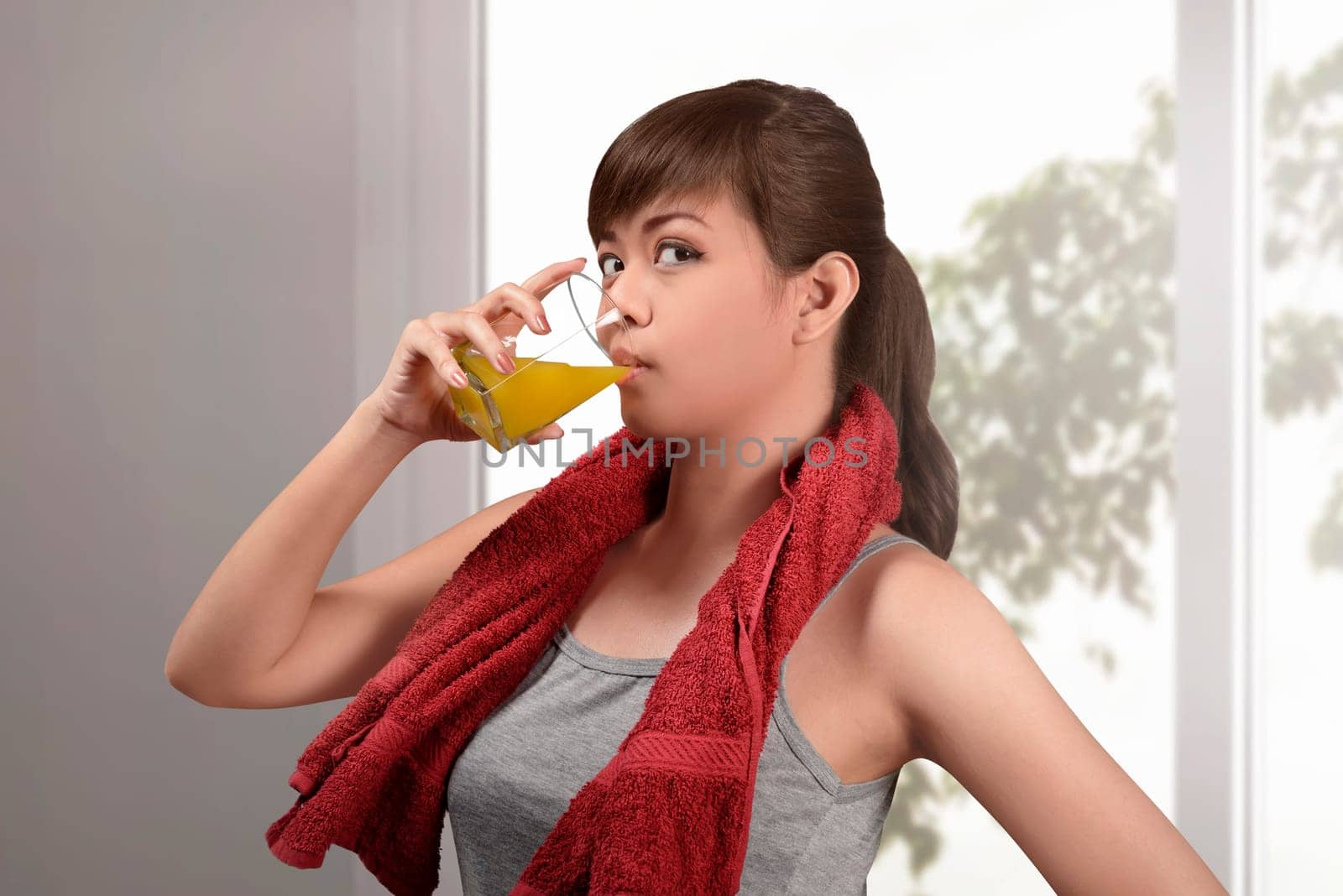 Happy asian woman drink natural orange juice at home