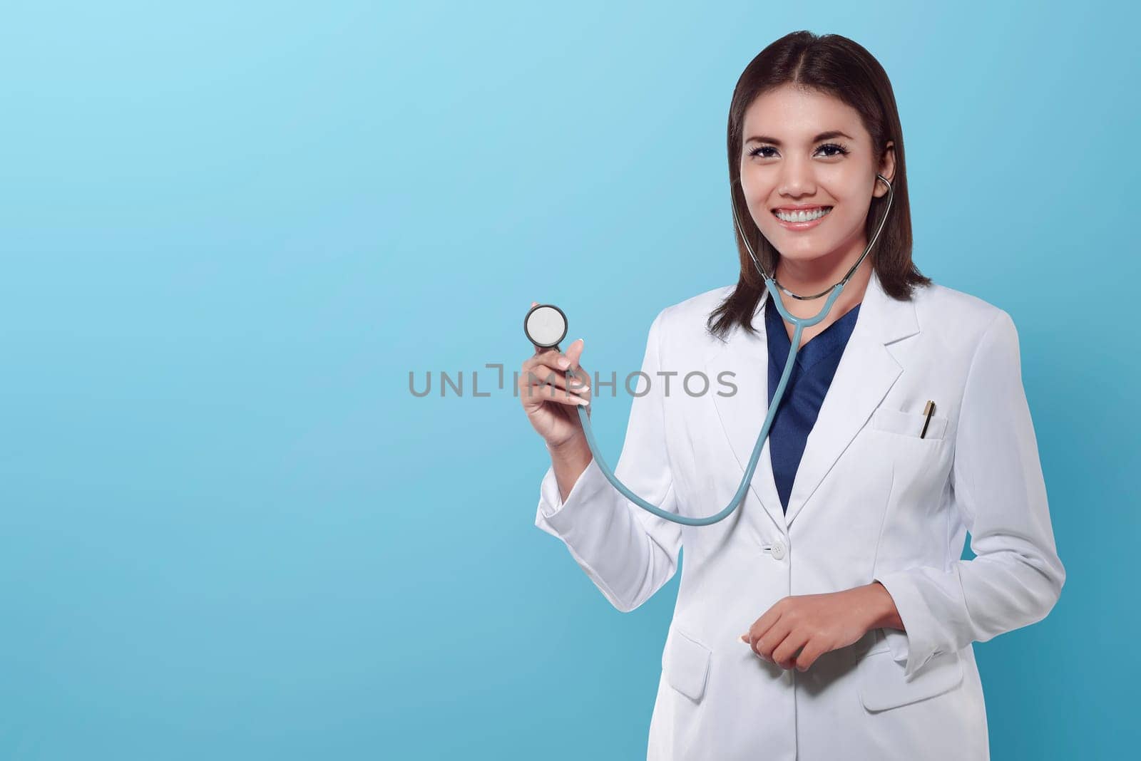 Young asian doctor woman holding stethoscope over blue background