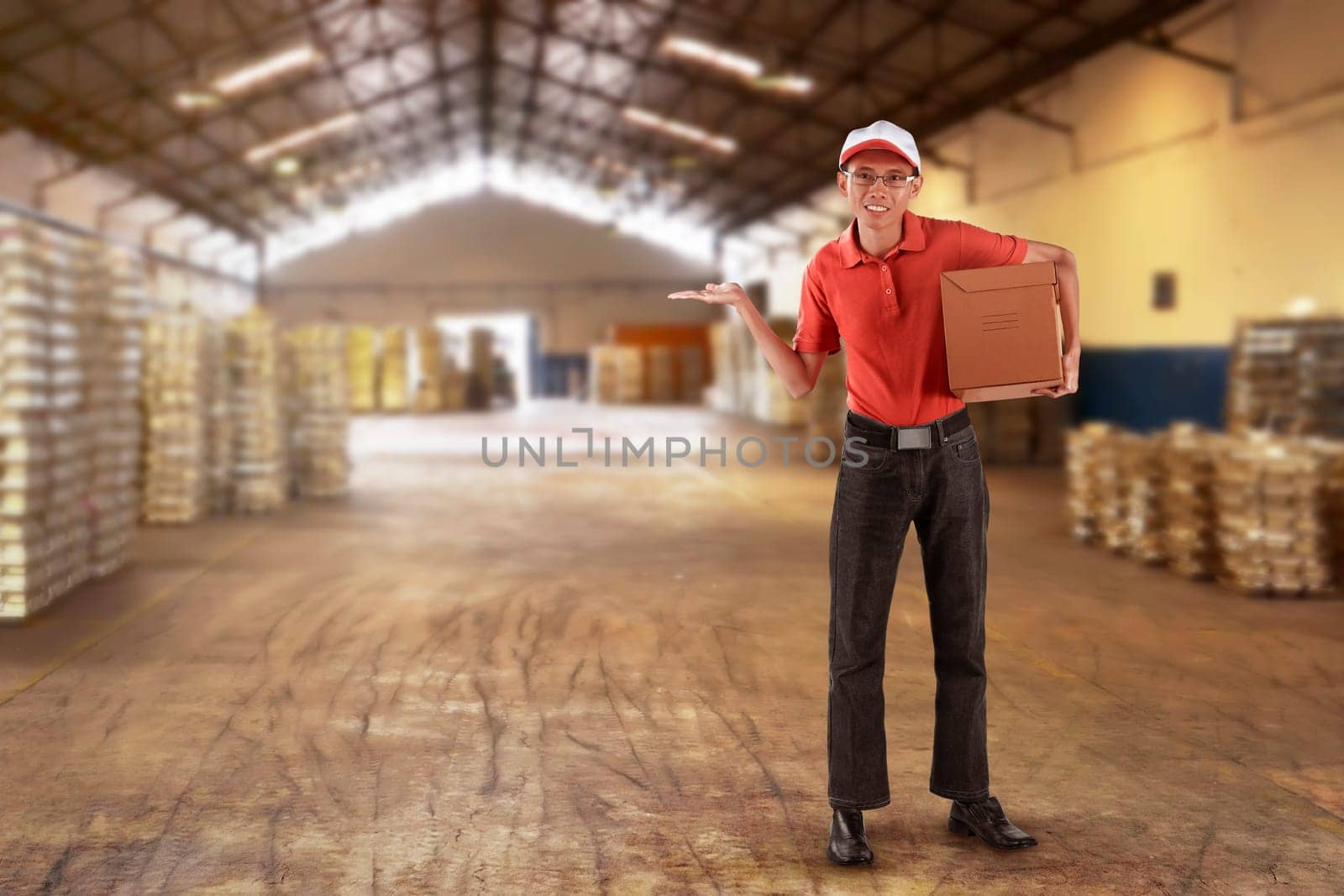 Asian male courier delivery holding package with open arm on the warehouse