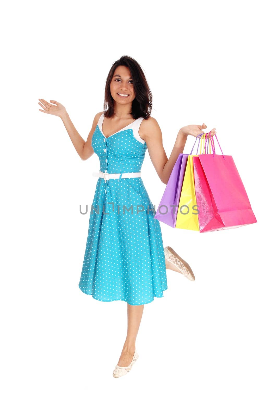 A happy young woman in a blue dress holding up some shopping.colorful bags, smiling, isolated for white background. .