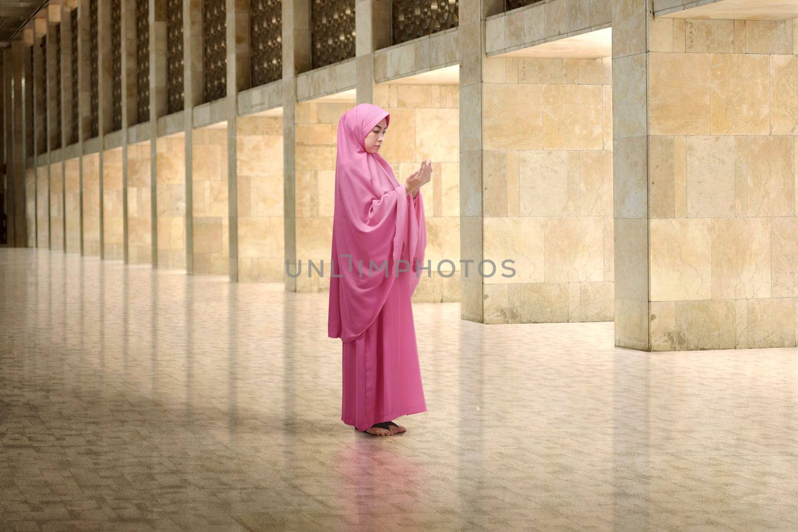 Young asian muslim woman with veil dress praying in the mosque