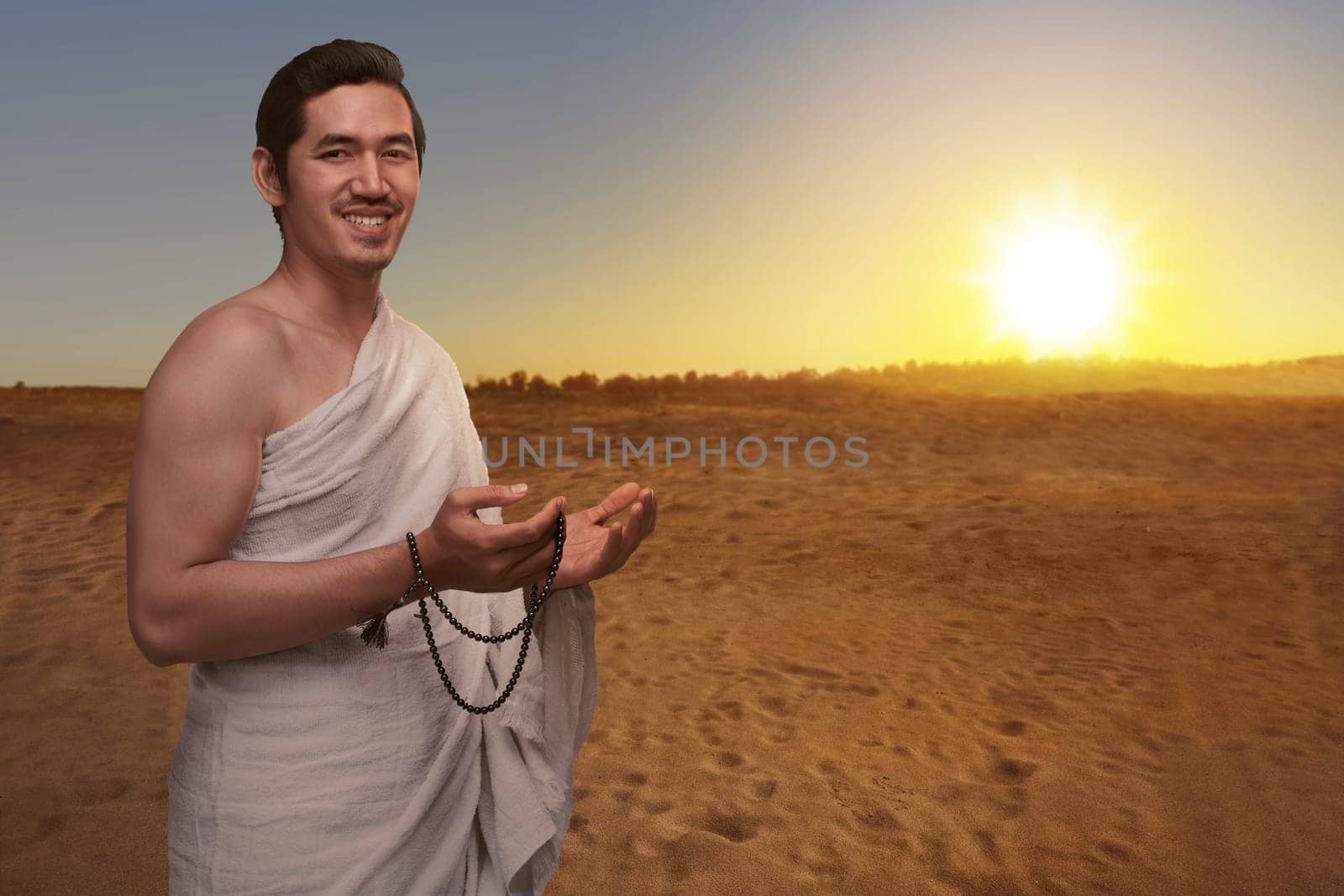 Handsome asian muslim man in ihram dress with prayer beads ready for hajj