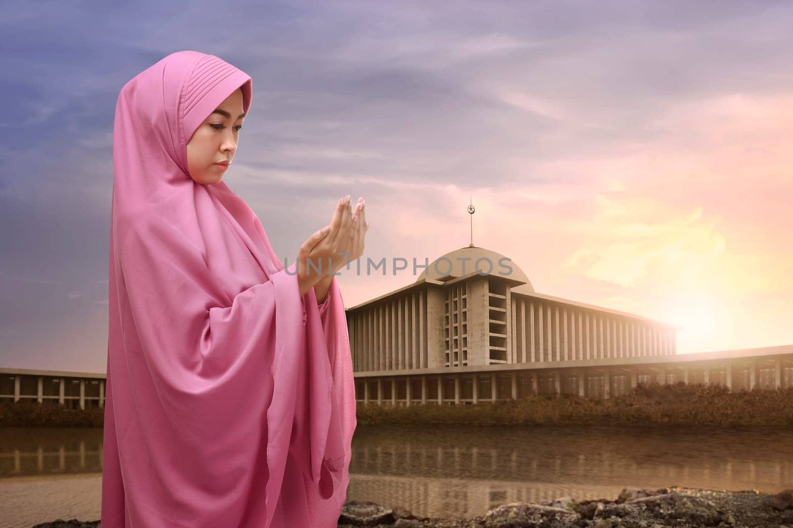 Portrait of asian muslim woman in hijab praying with mosque background