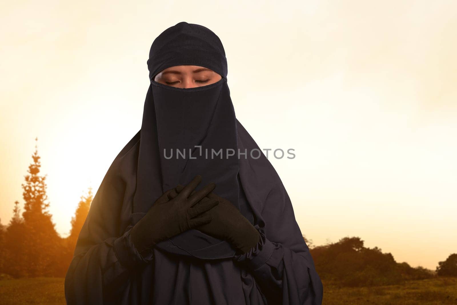 Beautiful asian muslim female in veil with niqab standing on the field