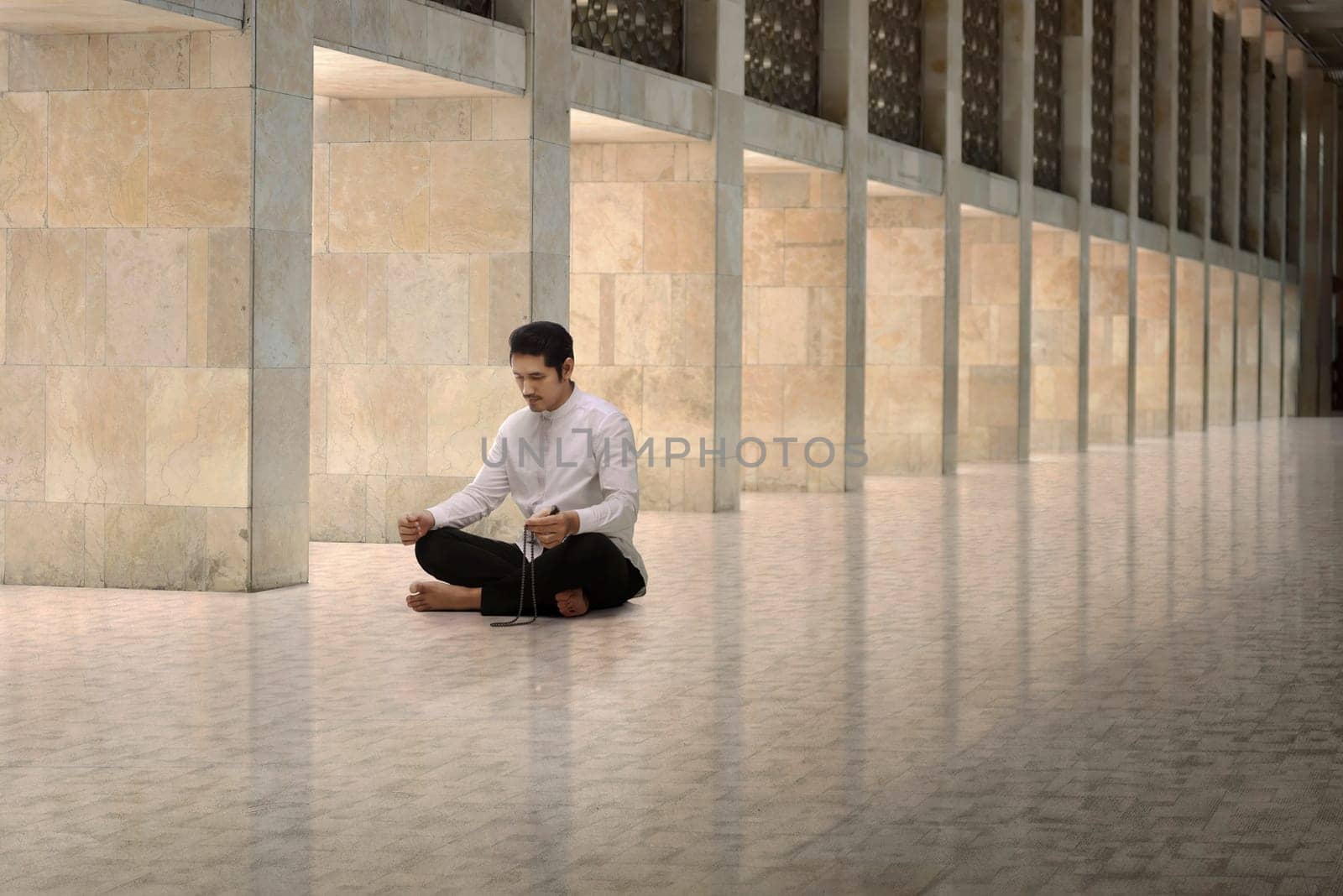 Religious asian muslim man with prayer beads praying in the mosque