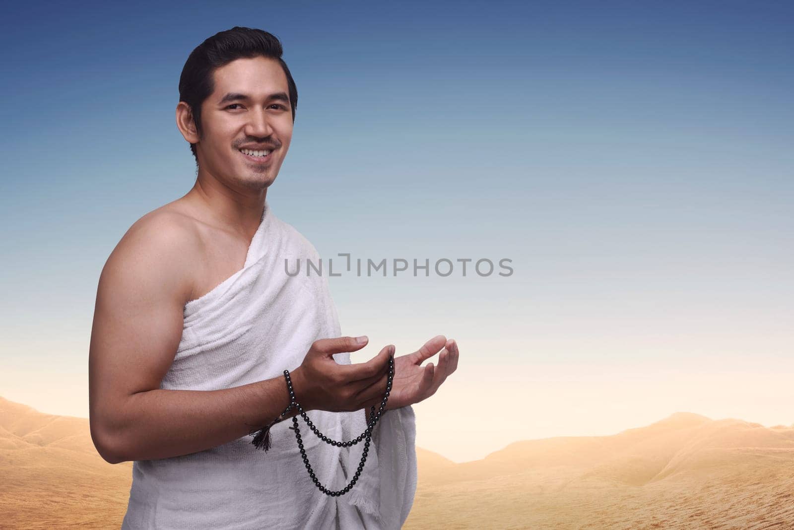 Happy asian muslim man wearing ihram clothes and prayer beads ready for hajj