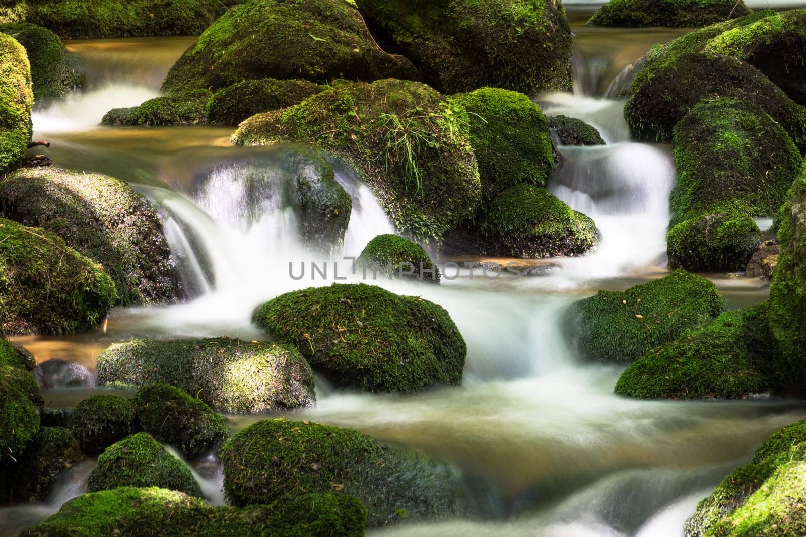 Mountain stream in the forest,waterfall with moss covered stones and long exposure