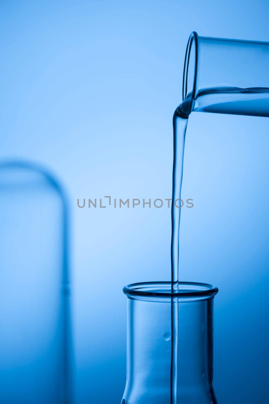 Filling an Erlmeyer flask from a reagent laser against a blue tinted studio background.