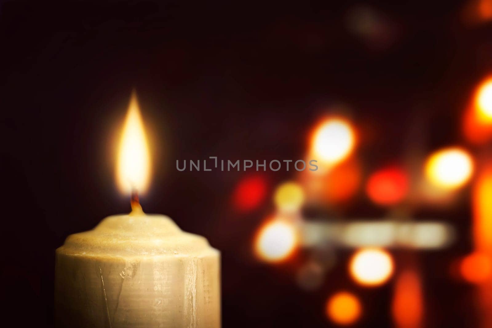 Burning candle against blurred light background