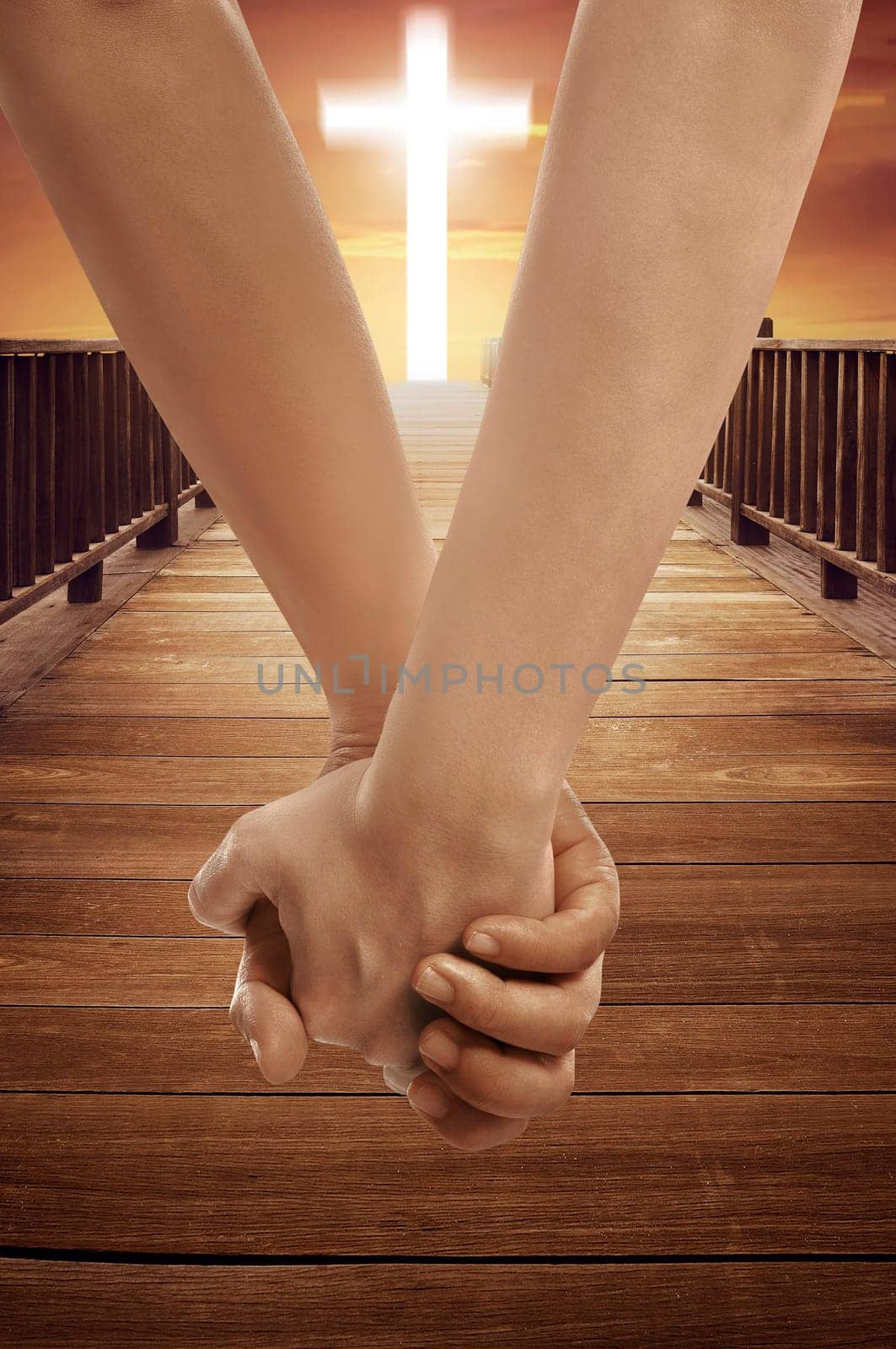 Man and woman holding hand together with cross religion symbol on sunset sky