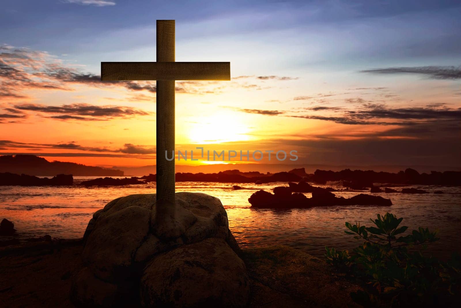 Christian cross on the rock in beach at sunset