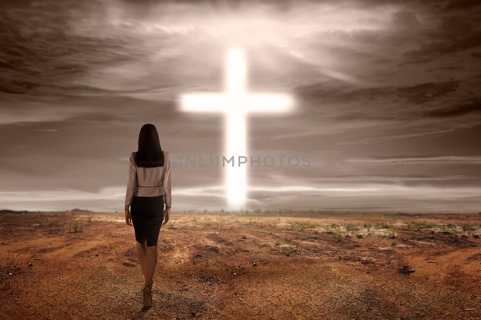 Back view asian woman walking to bright cross shape on dry land background