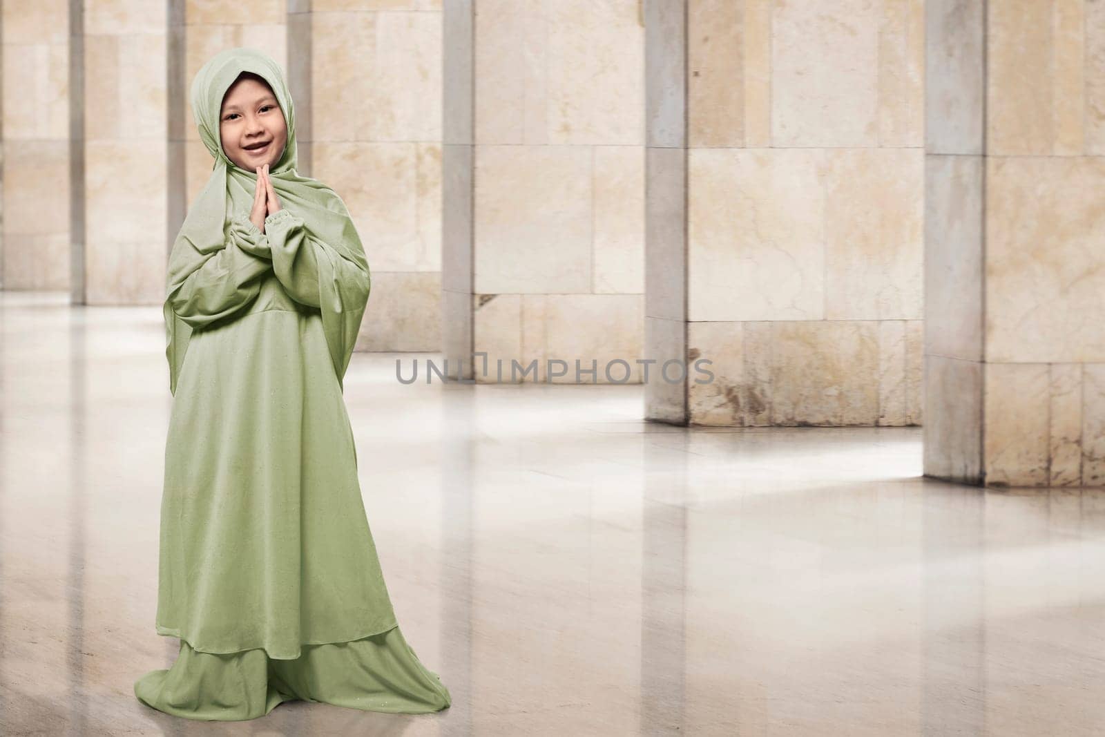 Asian muslim kid in green hijab clothes praying in the mosque