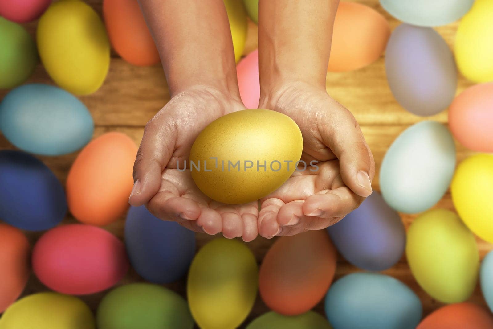 People hand holding gold Easter eggs against pile of colorful Easter eggs