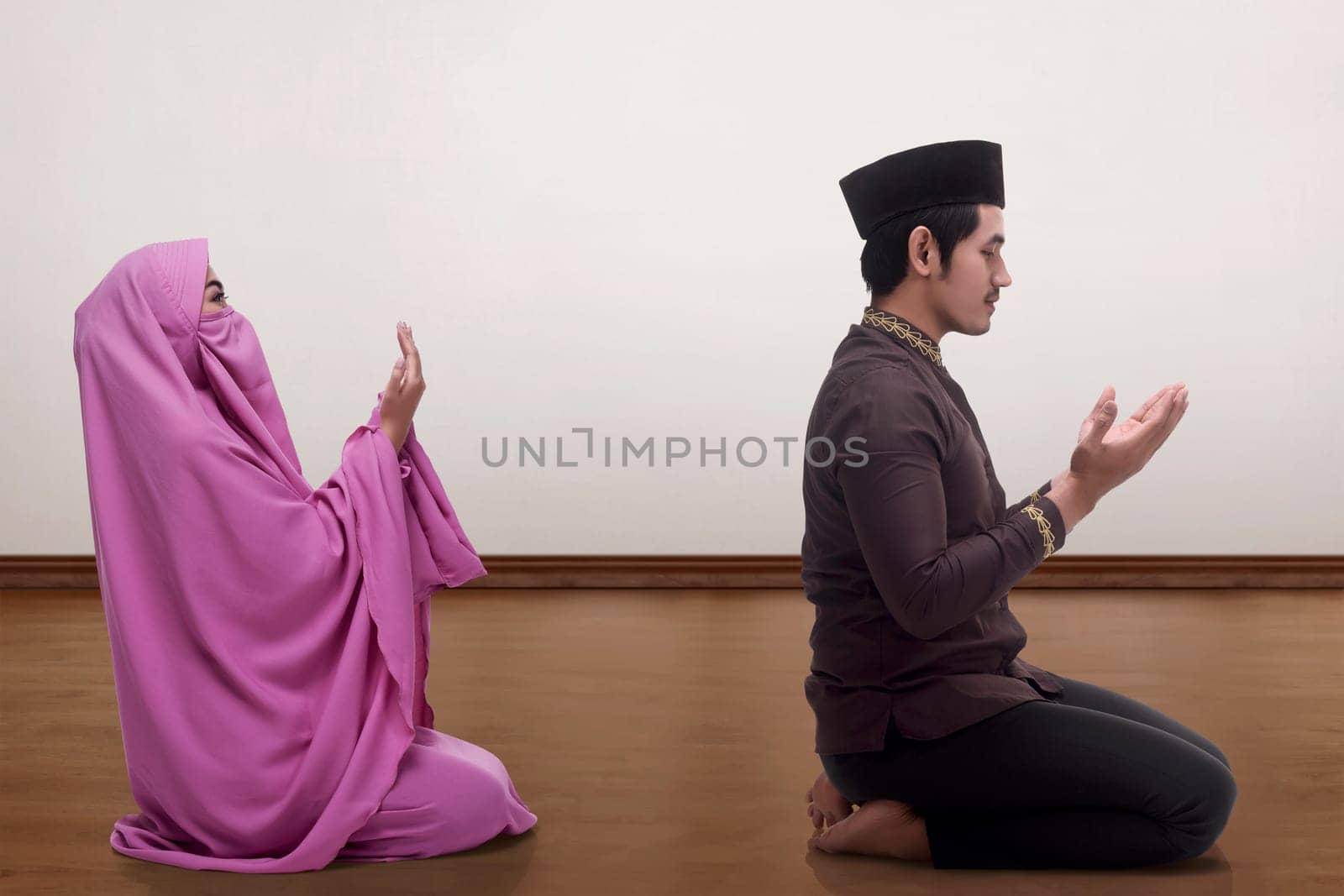 Asian muslim man and woman praying together inside the room