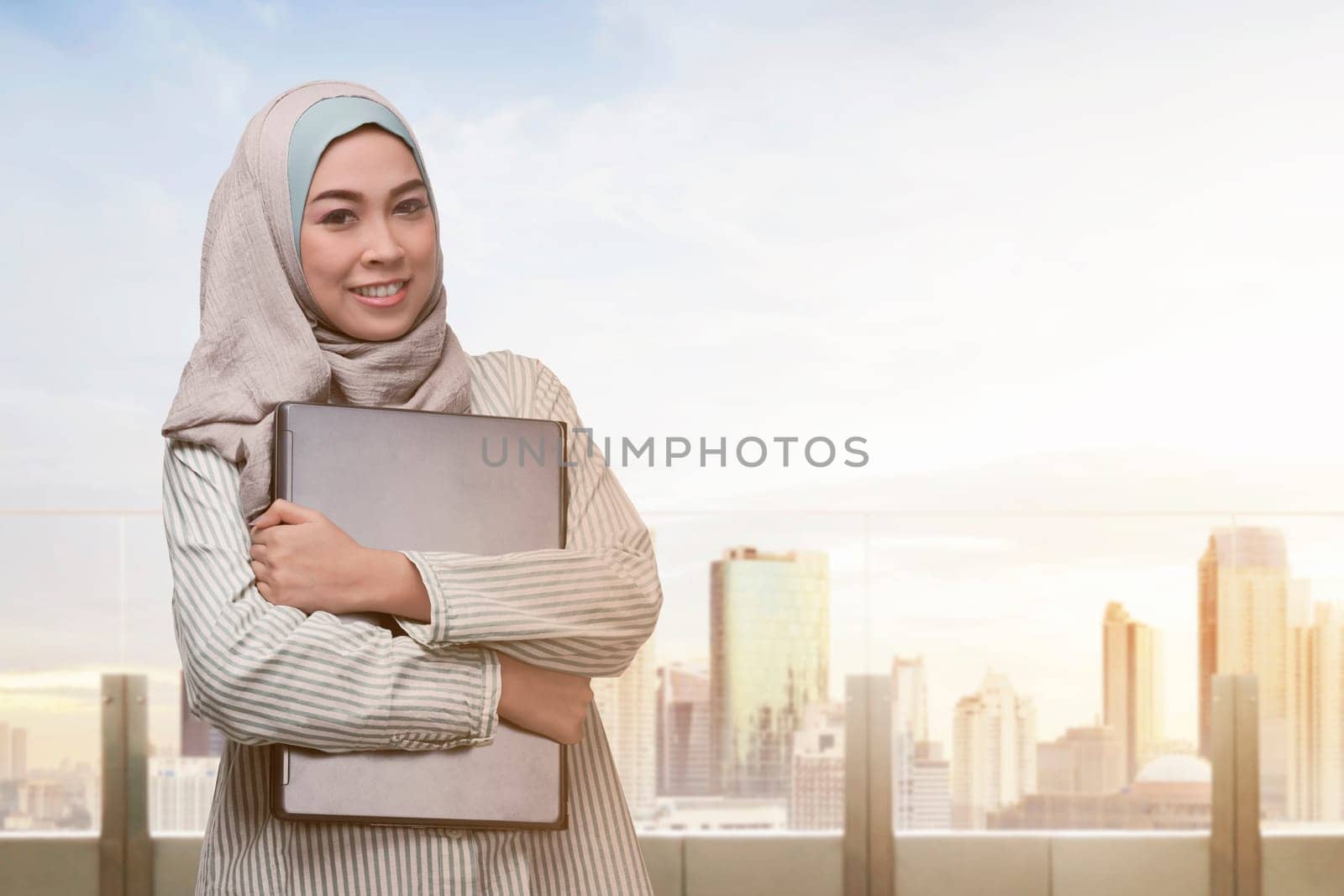 Portrait of asian muslim woman standing with laptop in the office terrace