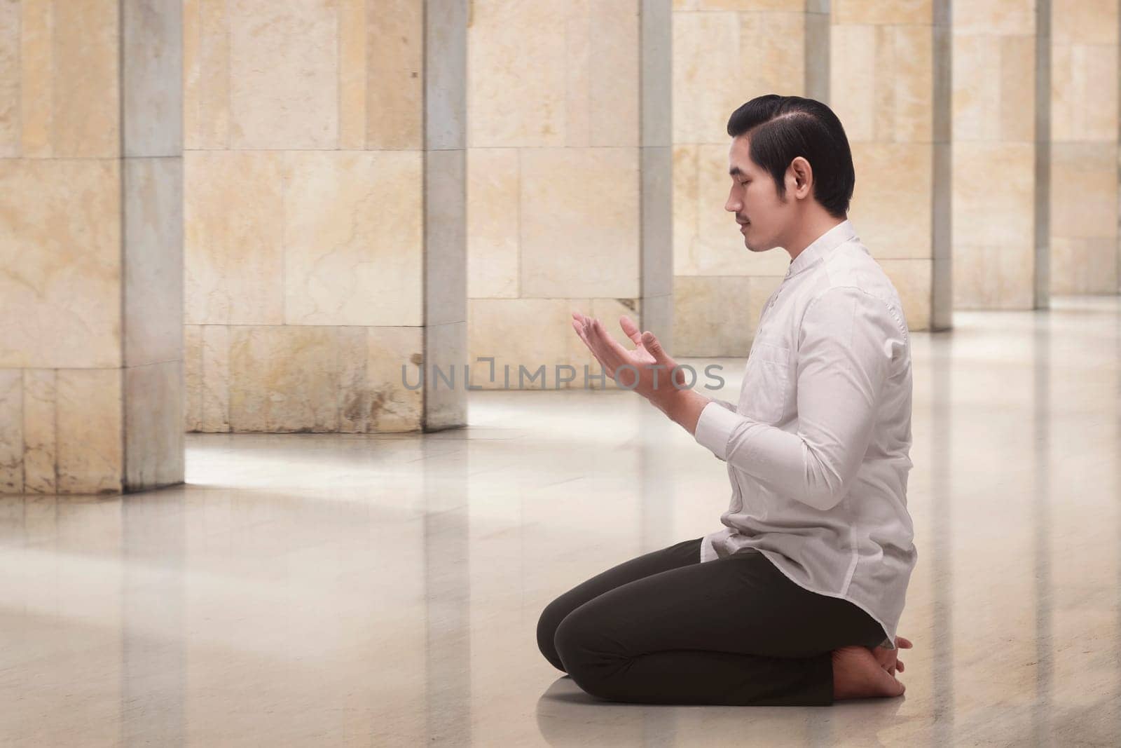 Handsome asian muslim man kneeling while praying in the mosque