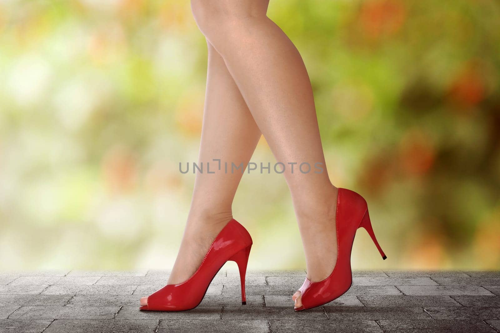 Woman legs in red high heels walking on urban street
