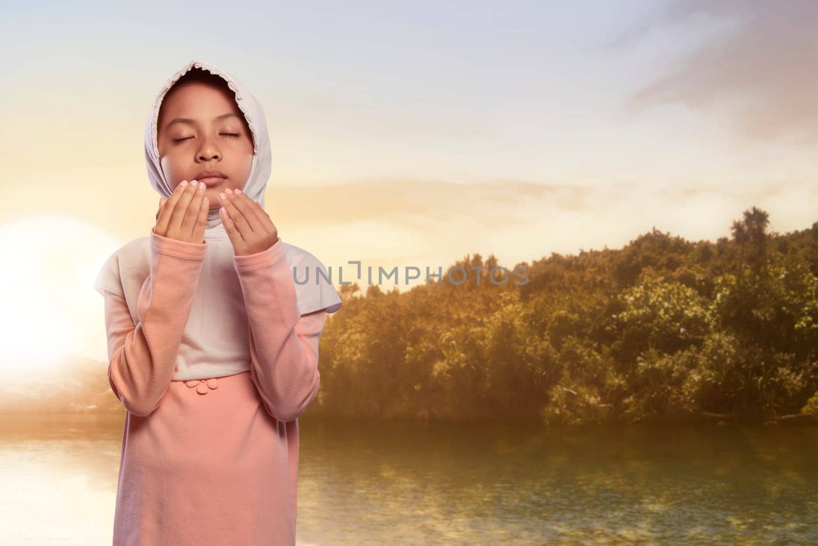 Pretty asian muslim child with hijab praying with scenics background