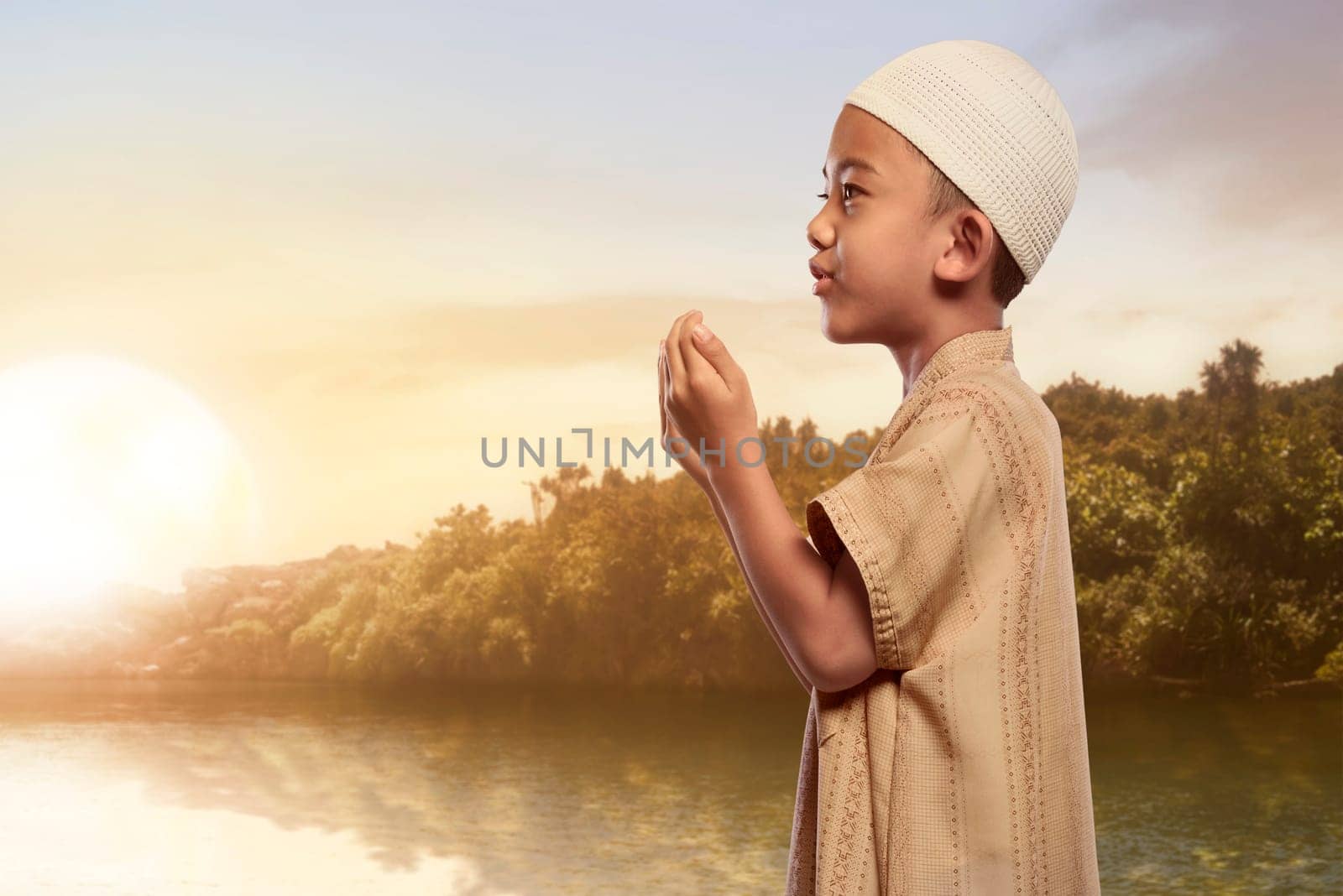 Asian muslim boy with traditional dress praying at outdoor