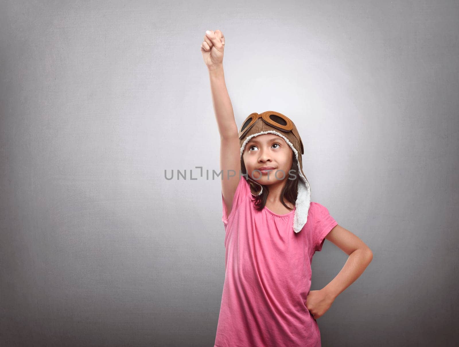 Happy asian child in pilot aviator playing and dreams over grey wall background