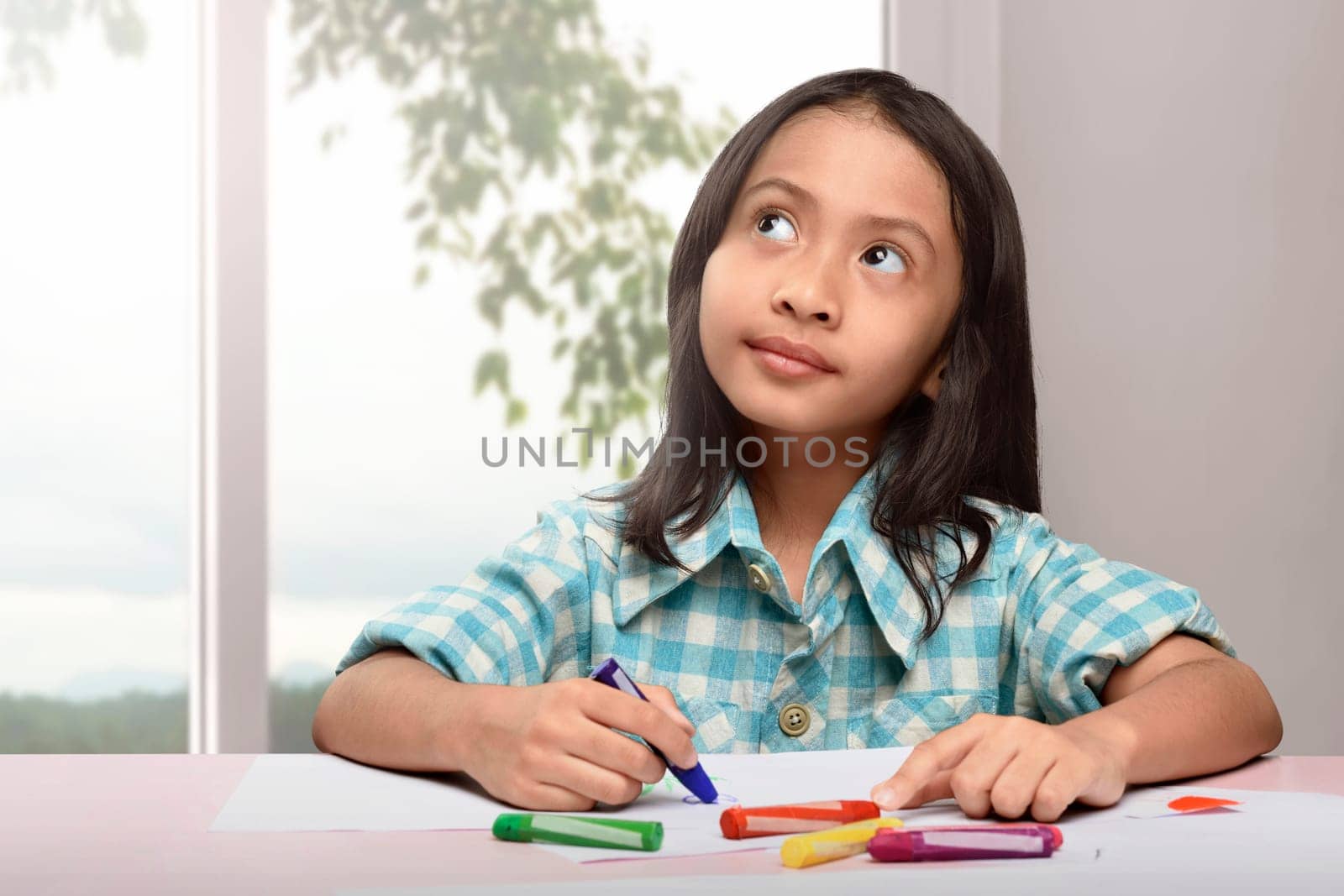 Cute asian little child drawing with colorful crayon at home